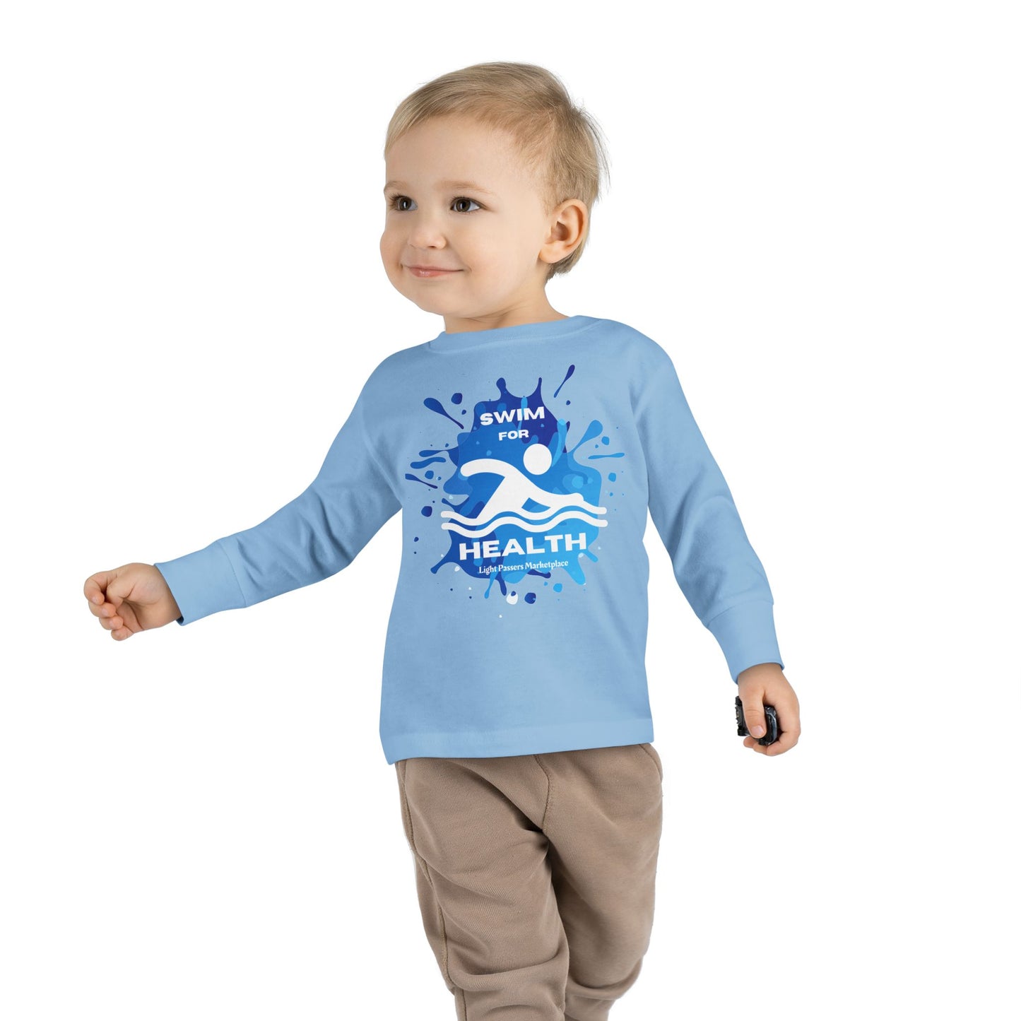 Toddler wearing a long sleeve swim tee, walking towards the camera, showcasing the tee’s comfortable fit and ribbed cuffs. Perfect for pool or beach play.