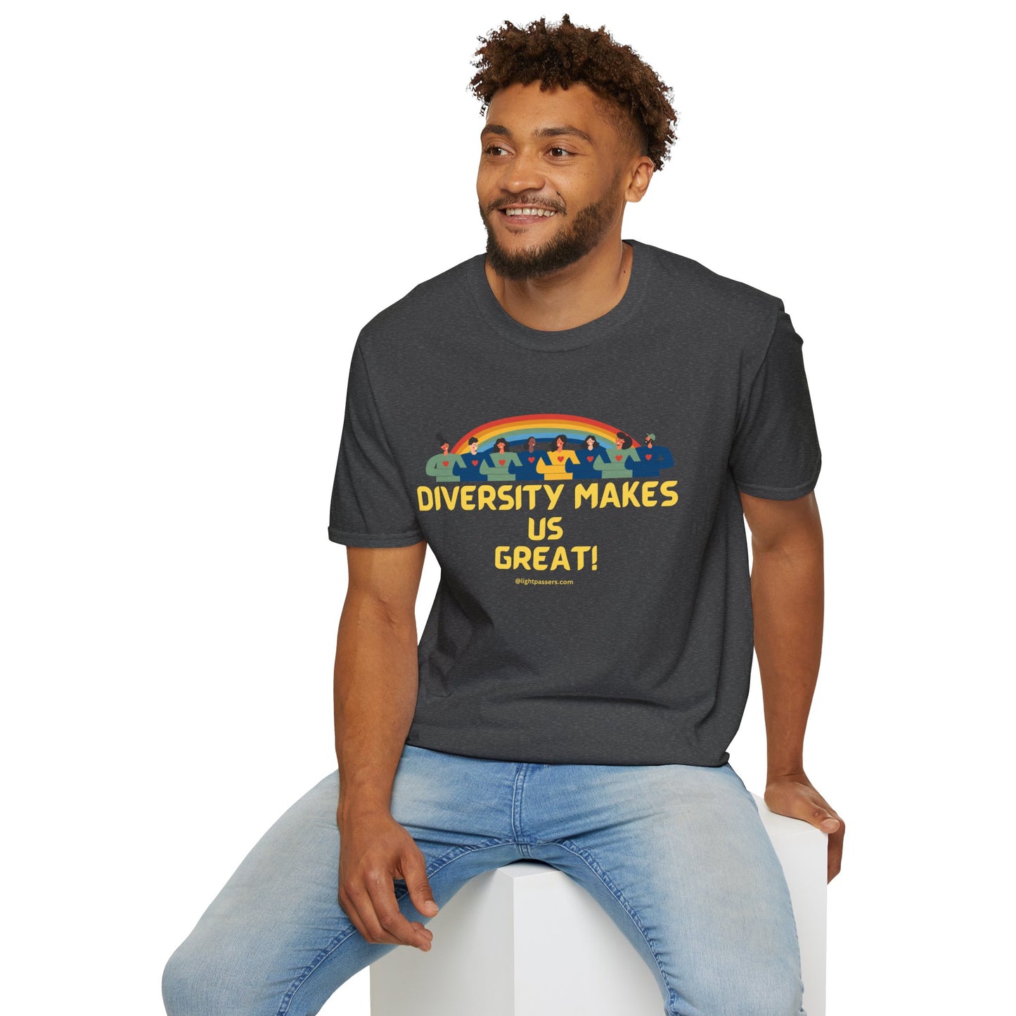 A man in a grey shirt with yellow text sits on a cube, showcasing a unisex heavy cotton tee. The tee features smooth fabric for vibrant printing and durable tape on the shoulders.