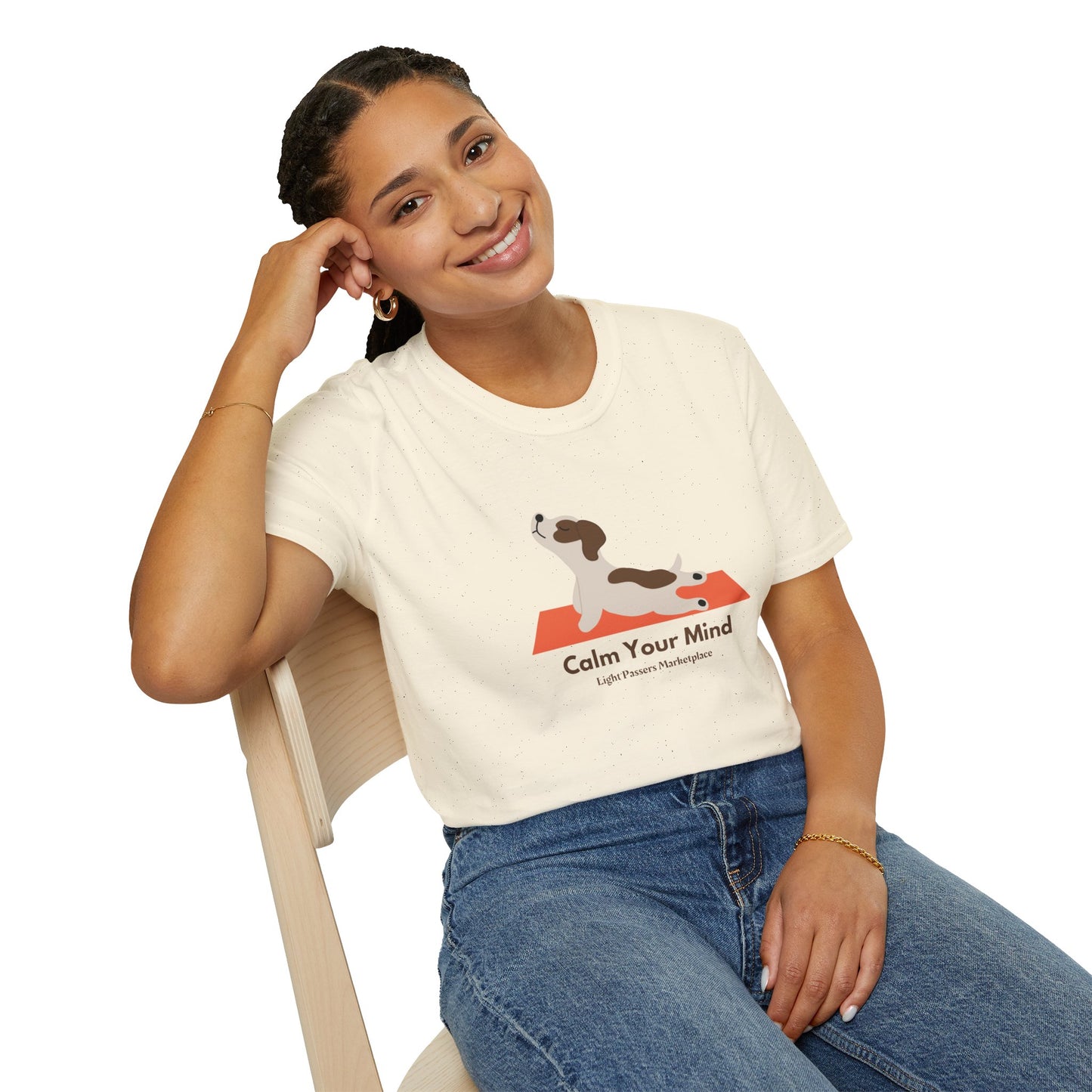 A woman in a Calm Dog Yoga Unisex T-shirt sits on a chair, smiling. The soft tee, made of 100% cotton, offers comfort and durability with twill tape shoulders and a ribbed collar.