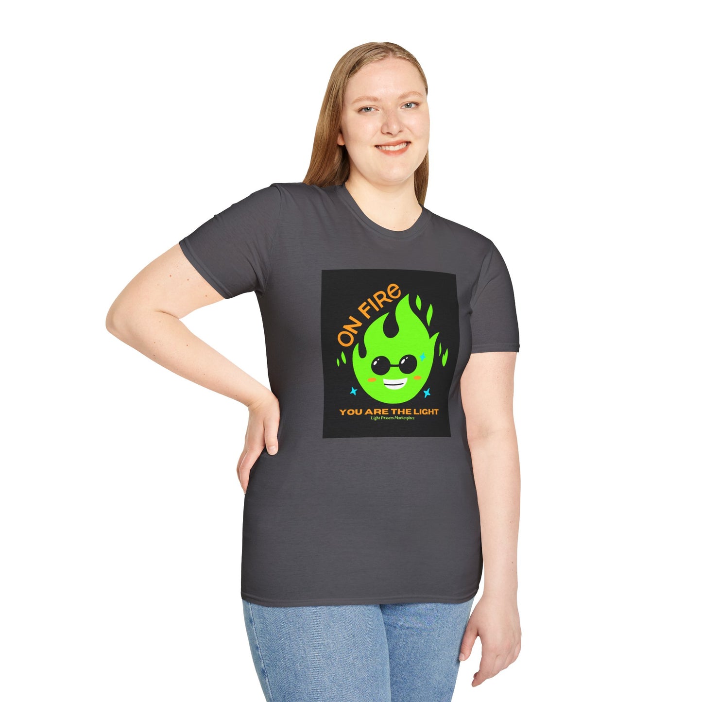 A woman in a grey shirt poses, showcasing a t-shirt with a green fire and yellow text. Close-up of blue jeans. Unisex soft-style tee, 100% cotton, twill tape shoulders, no side seams, ribbed collar.