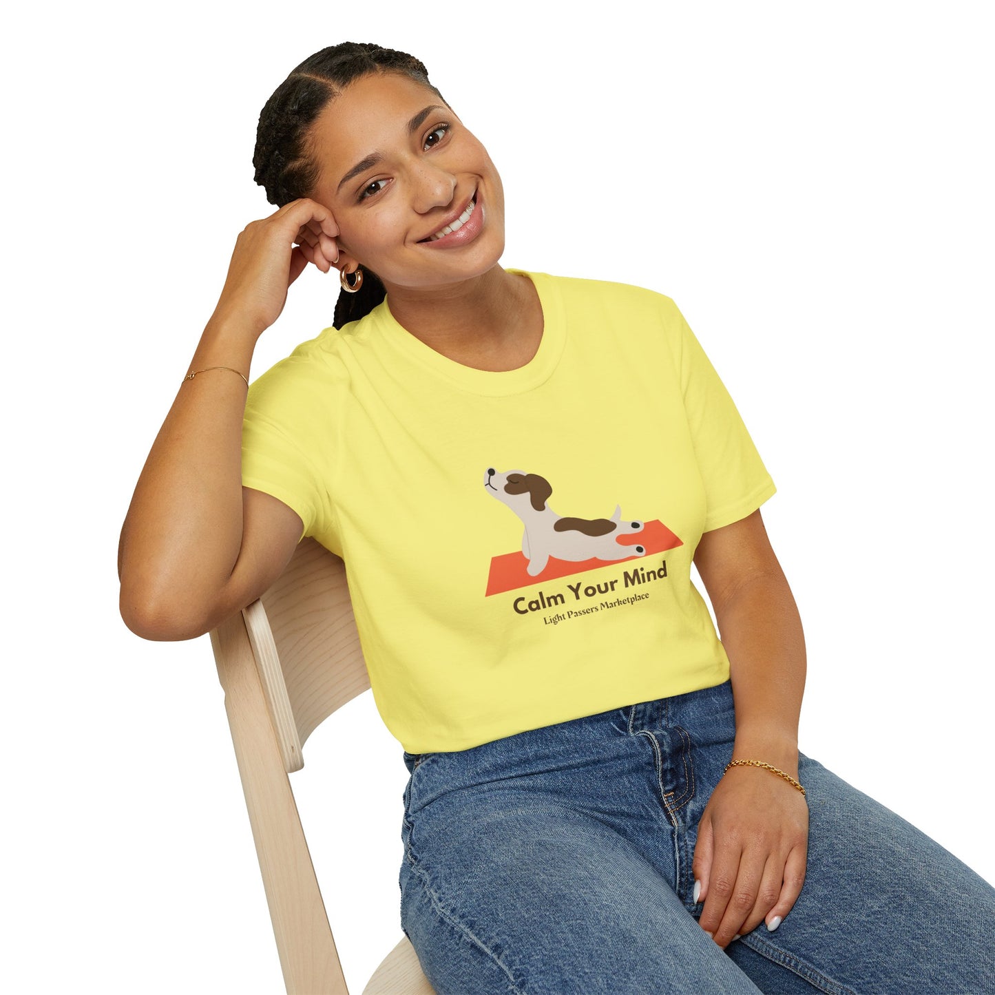 A woman in a yellow shirt sits on a chair, smiling, showcasing the Calm Dog Yoga Unisex T-shirt. Soft 100% cotton, twill tape shoulders, no side seams, ribbed collar. Ethically made, lightweight, versatile style.