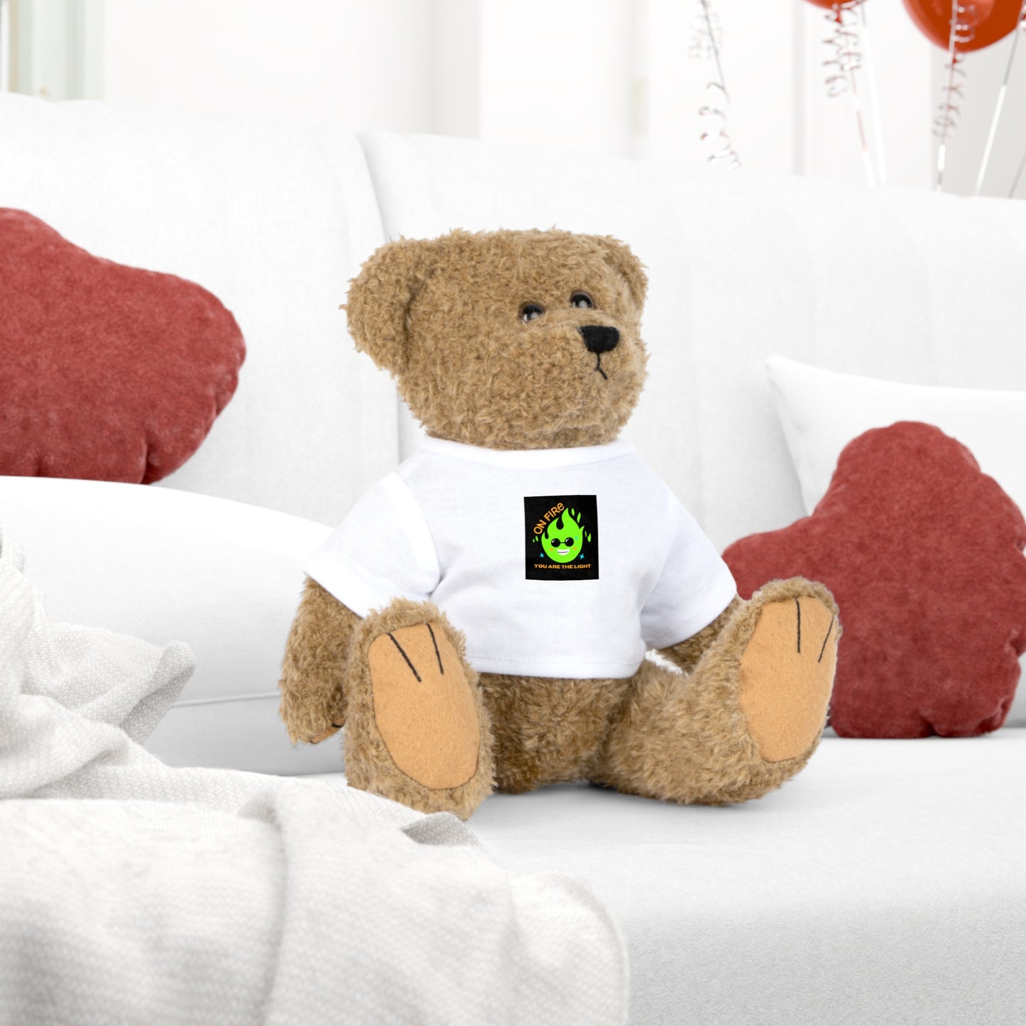 Plush Toy Bear Stuffie wearing a white shirt with On Fire You are the Light text, sitting on a couch.