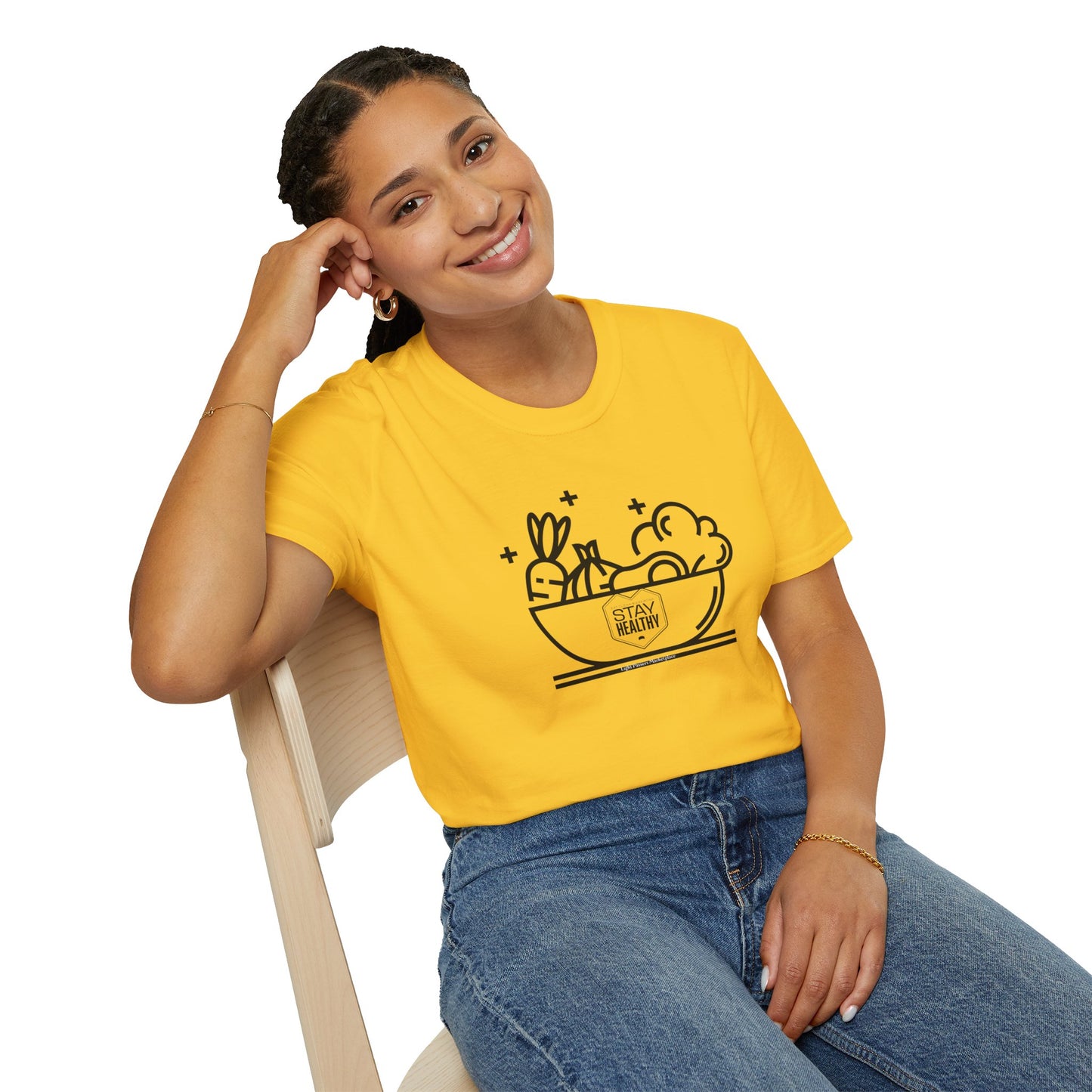 A woman in a yellow shirt sits on a chair, smiling. Stay Healthy Unisex T-Shirt, 100% cotton, no side seams, ribbed collar, ethically made, lightweight fabric, classic fit.
