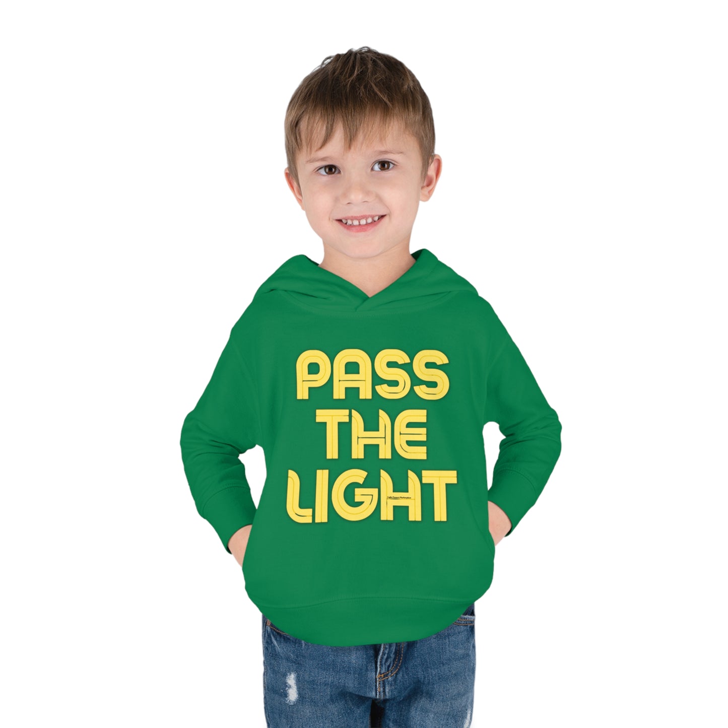 A toddler boy in a Pass the Light hoodie, showcasing a green sweatshirt with yellow text. Features jersey-lined hood, double-needle stitching, side pockets, and durable design for lasting coziness.