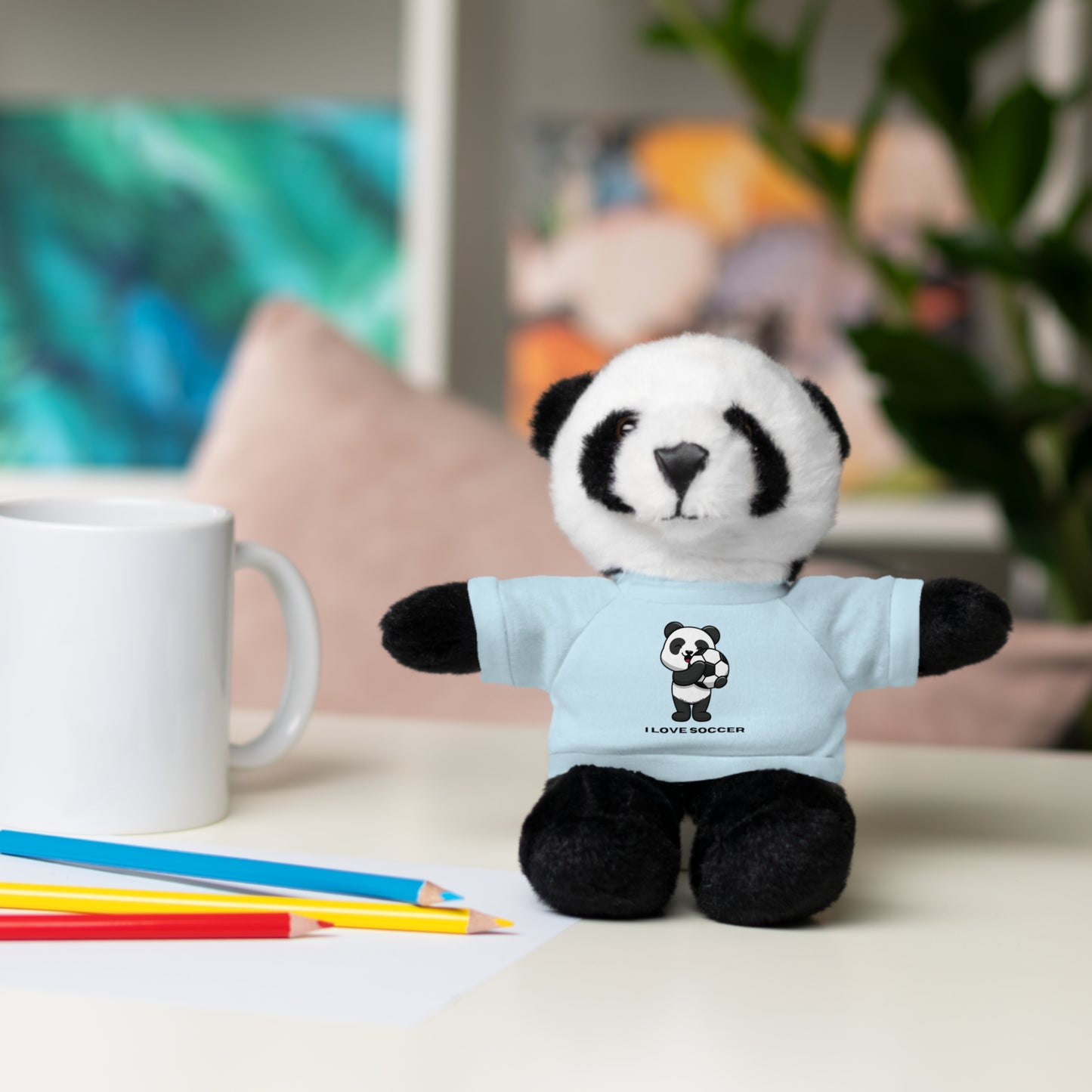 Panda Stuffed Animal with I Love Soccer Shirt: plush panda toy wearing a soccer-themed t-shirt, displayed on a table, ideal for kids and soccer enthusiasts.