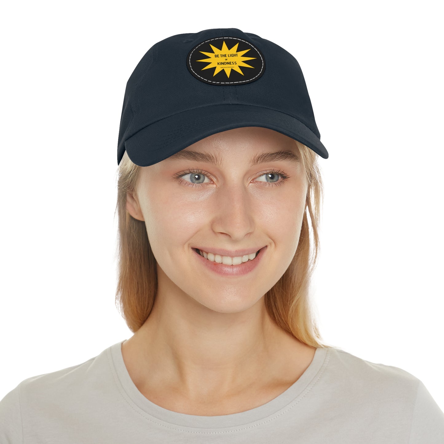 Unisex hat with 'Be the Light of Kindness' on PU leather patch, worn by a woman. Features chino twill fabric and buckle closure for a vintage look.