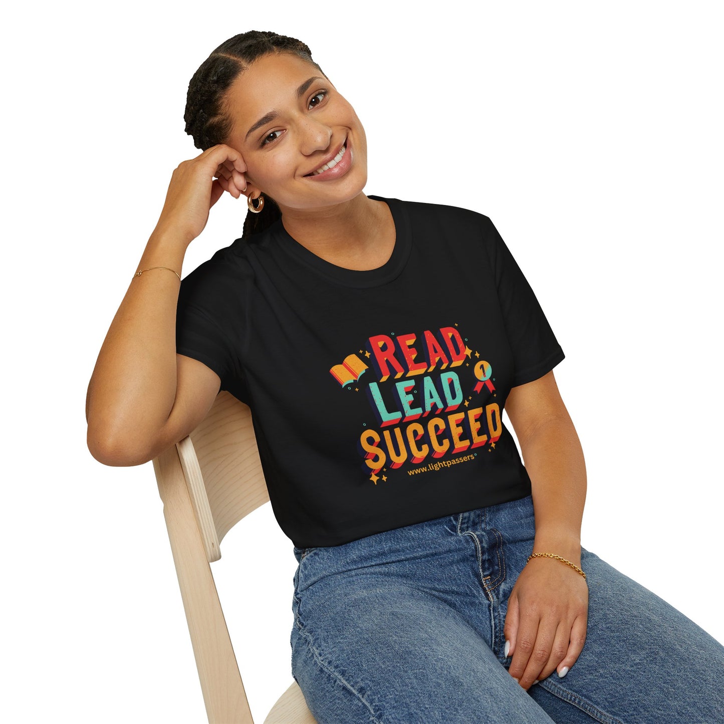 A smiling woman in a black shirt sits on a chair, showcasing the Read Lead Succeed Unisex T-Shirt. Soft 100% cotton, twill tape shoulders, no side seams, ribbed collar.
