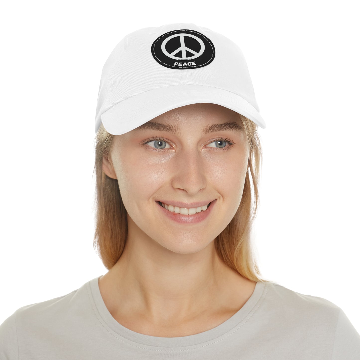 Unisex Hat with Leather Patch featuring a peace symbol, worn by a woman. Made of bio-washed chino twill, unstructured six-panel, low-profile design.