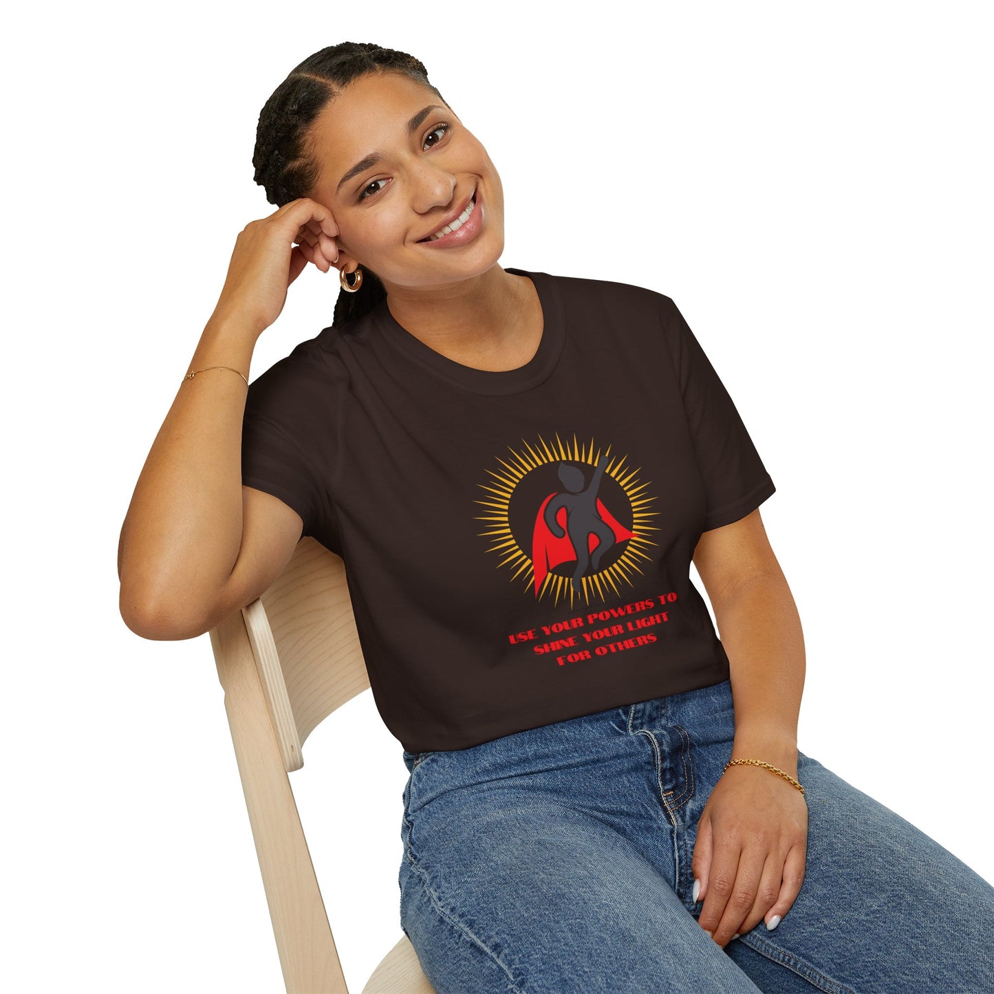 A smiling woman in a black shirt sits on a chair, showcasing the Use Your Powers Unisex T-shirt. The image features a superhero logo and a close-up of a book, embodying casual fashion with 100% cotton fabric and durable tape on the shoulders.
