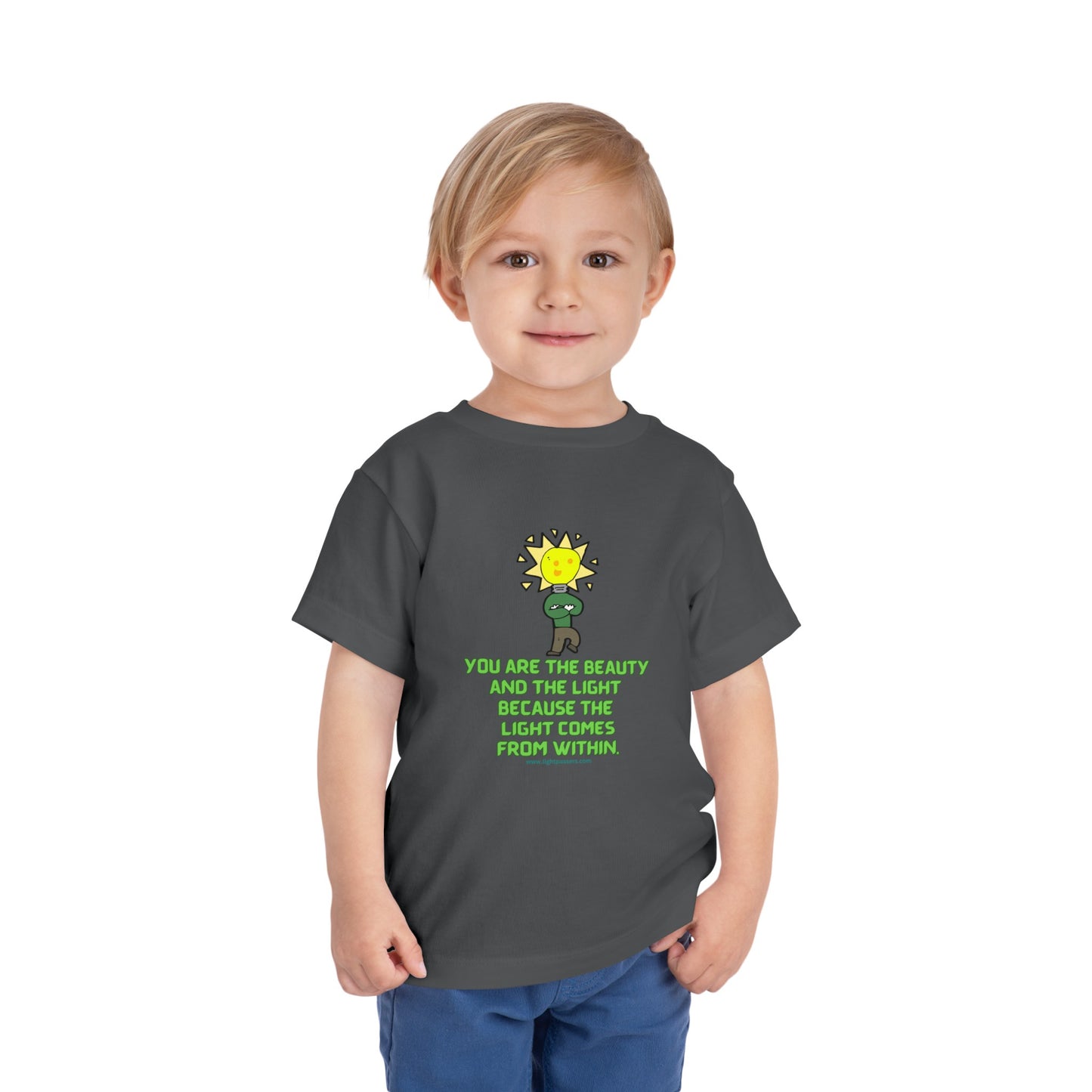 A toddler in a grey shirt with a light bulb cartoon character on the front, showcasing the Beauty and the Light Toddler T-shirt's playful design and airy Airlume cotton fabric.