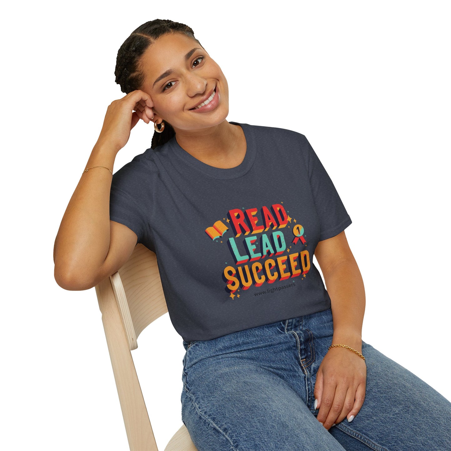 A smiling woman in a grey shirt sits on a chair, showcasing the Read Lead Succeed Unisex T-Shirt. Soft 100% cotton, twill tape shoulders, no side seams, ribbed collar.
