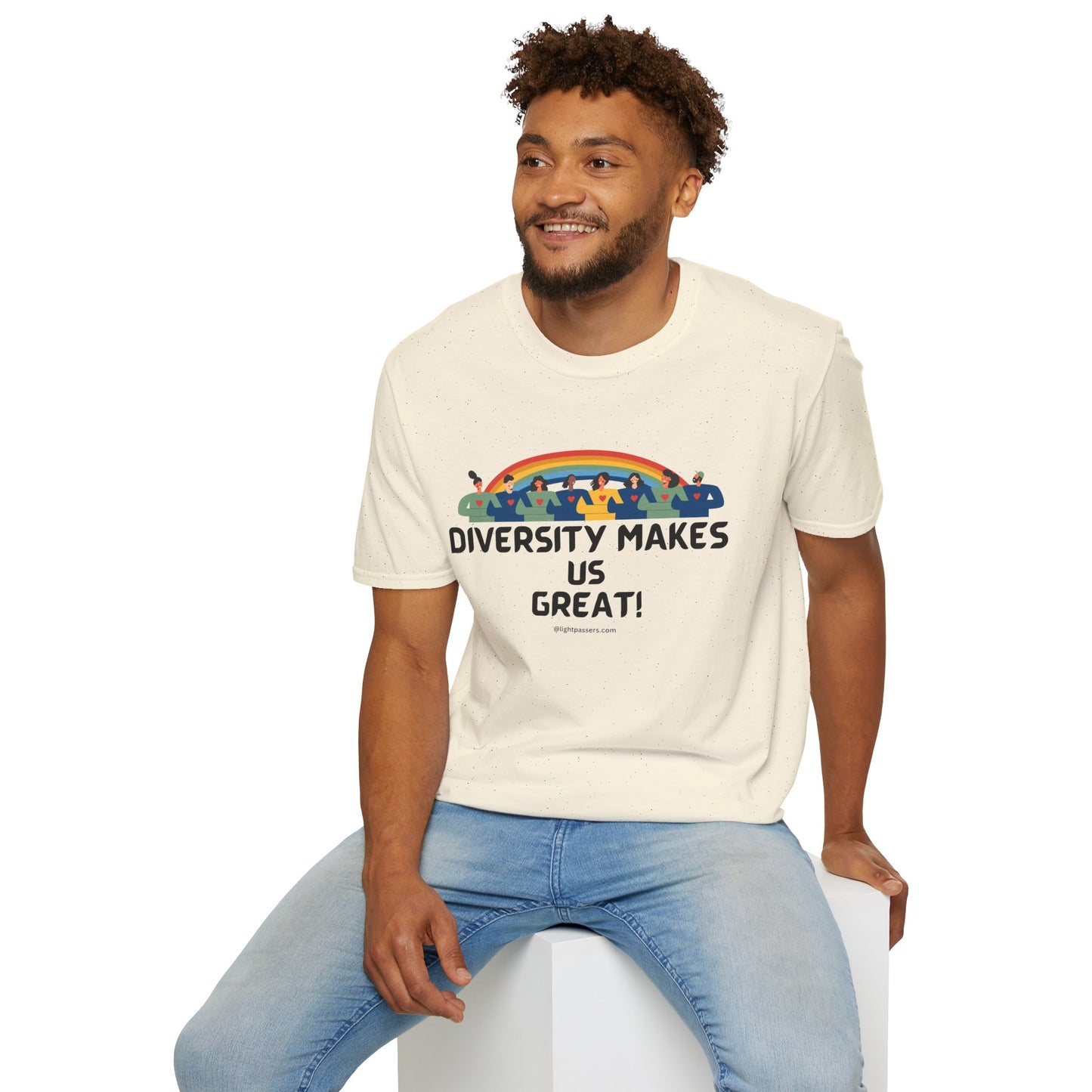 A man in a white shirt with a rainbow and people design sits on a cube, showcasing the Diversity Makes Us Great unisex T-shirt. Classic fit, 100% cotton, tear-away label for comfort.