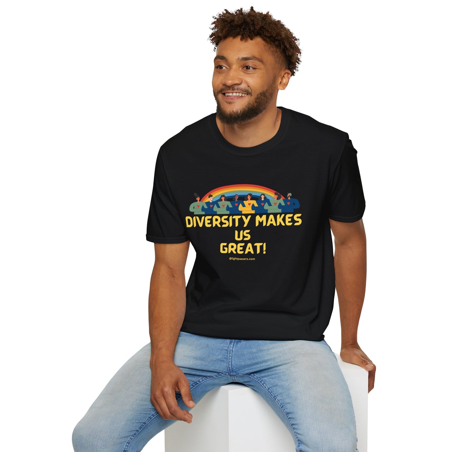A man in a black shirt sits on a cube, showcasing the Diversity Makes Us Great yellow text Unisex T-shirt. The image features a person with curly hair and beard smiling, emphasizing the classic fit and 100% cotton fabric of the tee.