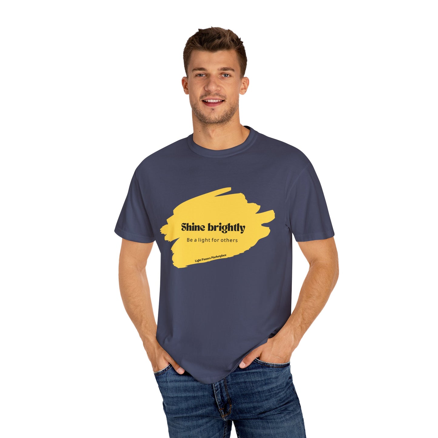 Man wearing 'The Light Shine Brightly for Others' T-shirt, hands in pockets, showcasing its relaxed fit and crew neckline, ideal for casual settings.