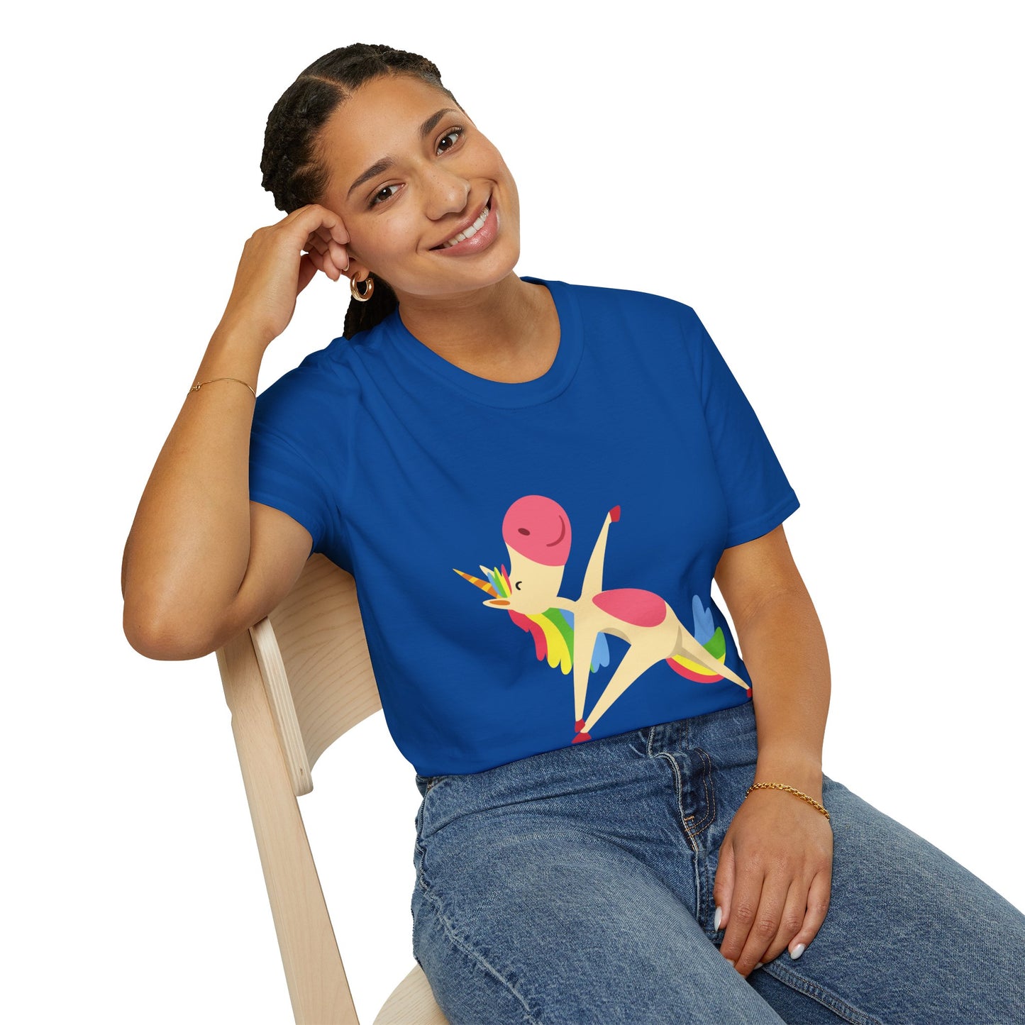 A woman in a Unicorn Stretch Yoga Unisex T-Shirt sits on a chair, smiling. The shirt features a unicorn design on a blue fabric, embodying comfort and style with 100% ring-spun cotton.
