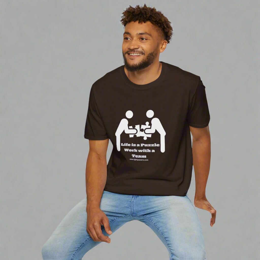 A man in a brown shirt, sitting on a cube, wearing a Life is a Puzzle Team Unisex T-shirt. Casual, heavy cotton tee with smooth surface for vivid printing.