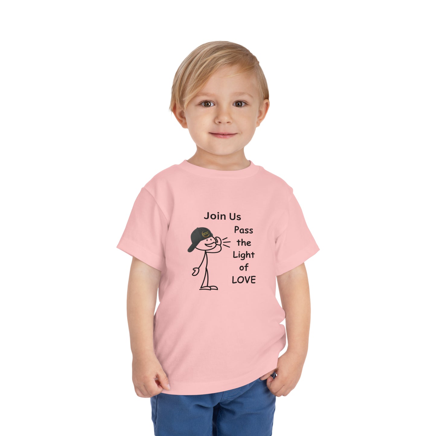 A toddler in a pink shirt, featuring a cartoon face with a hat, showcasing the Call Pass the Light of Love Toddler T-shirt. Made of 100% Airlume combed cotton for comfort.