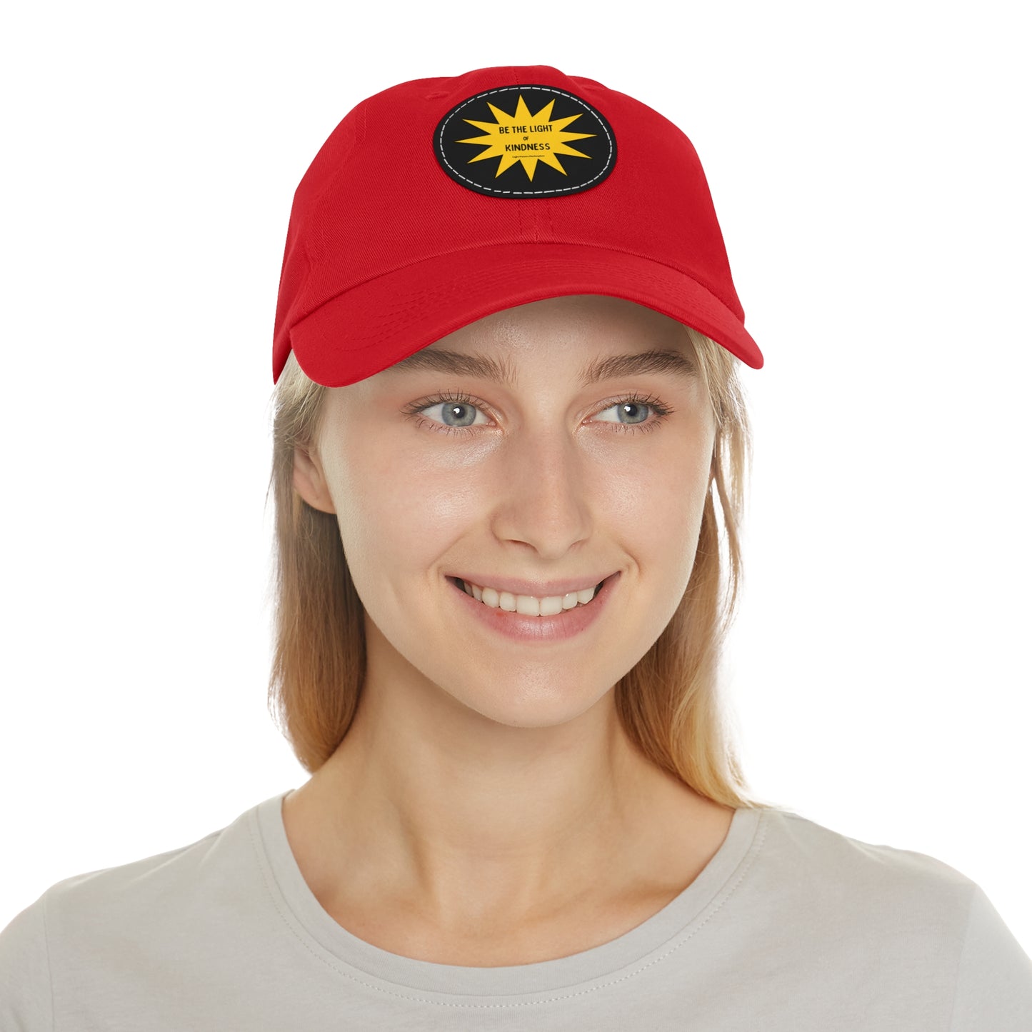 Unisex hat with 'Be the Light of Kindness' on PU leather patch, worn by a smiling woman. Ideal for casual wear and spreading positivity.
