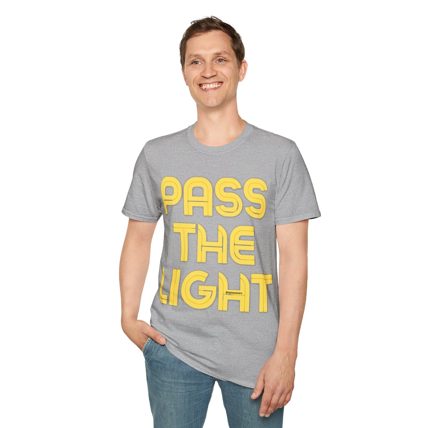 A smiling man in a PASS THE LIGHT Unisex T-shirt with hands in pockets. Grey shirt with yellow text. No side seams for comfort, 100% cotton.