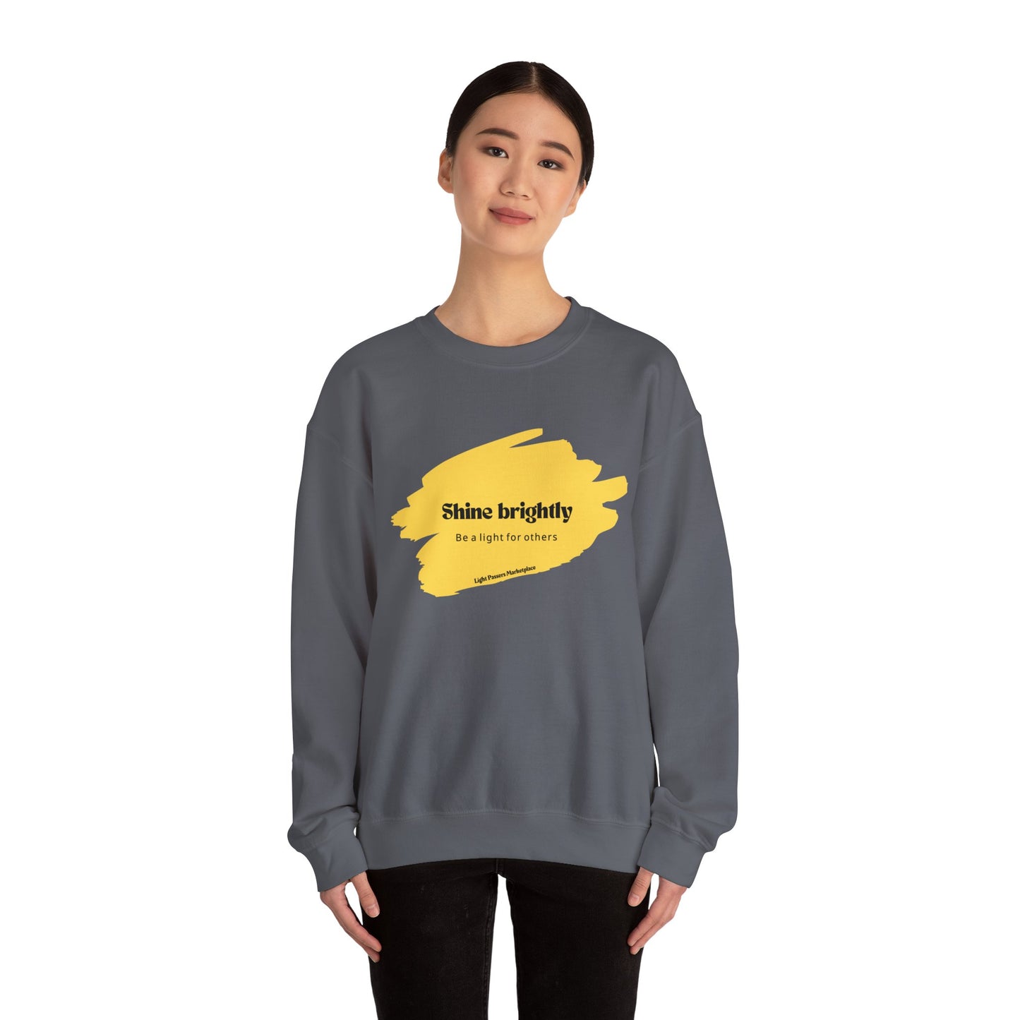 The Light Inspirational Crewneck Sweatshirt, featuring a yellow paint stroke with motivational text, worn by a woman for casual, cozy wear.