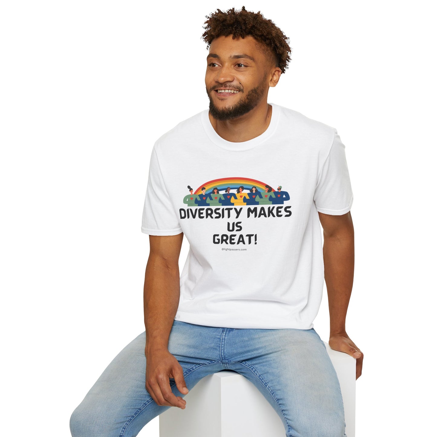 A man in a white shirt with a rainbow and people design sits on a cube, showcasing the Diversity Makes Us Great yellow text Unisex T-shirt. Cotton tee with smooth surface, no side seams, and tape on shoulders for durability.