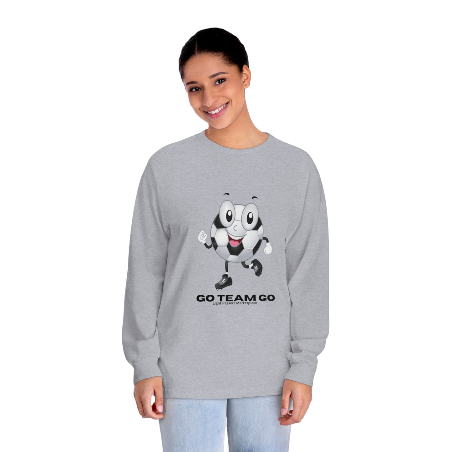 Woman wearing Soccer Ball Guy Long Sleeve Teams Adult Unisex shirt with cartoon football design, smiling. Ideal for sports fans and casual events.