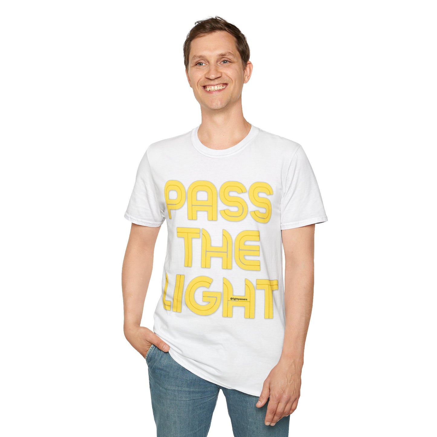 A man in a PASS THE LIGHT unisex t-shirt, smiling with hands in pockets. White shirt with yellow text, no side seams, smooth surface for premium printing.