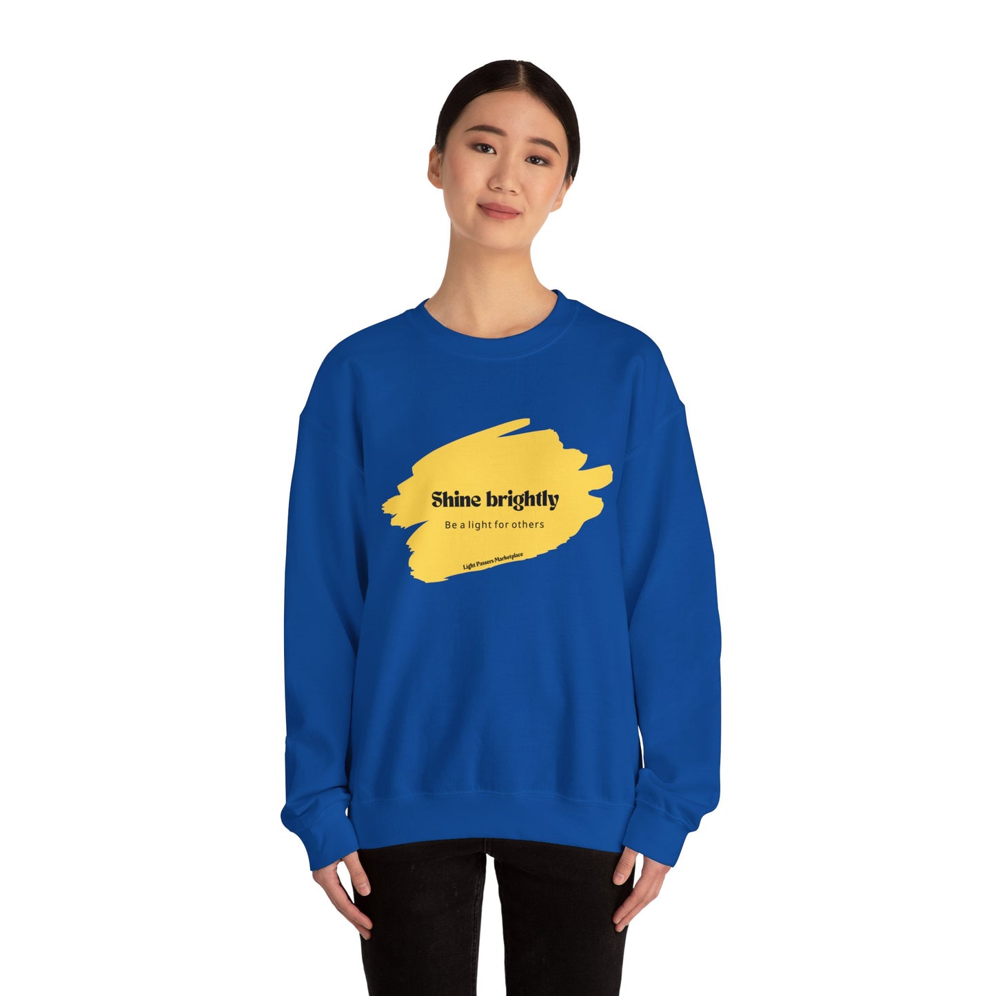 Woman in crewneck sweatshirt, Shine Brightly and Be the Light for Others, showcasing comfort with ribbed collar and ethically sourced materials. Ideal for casual wear.