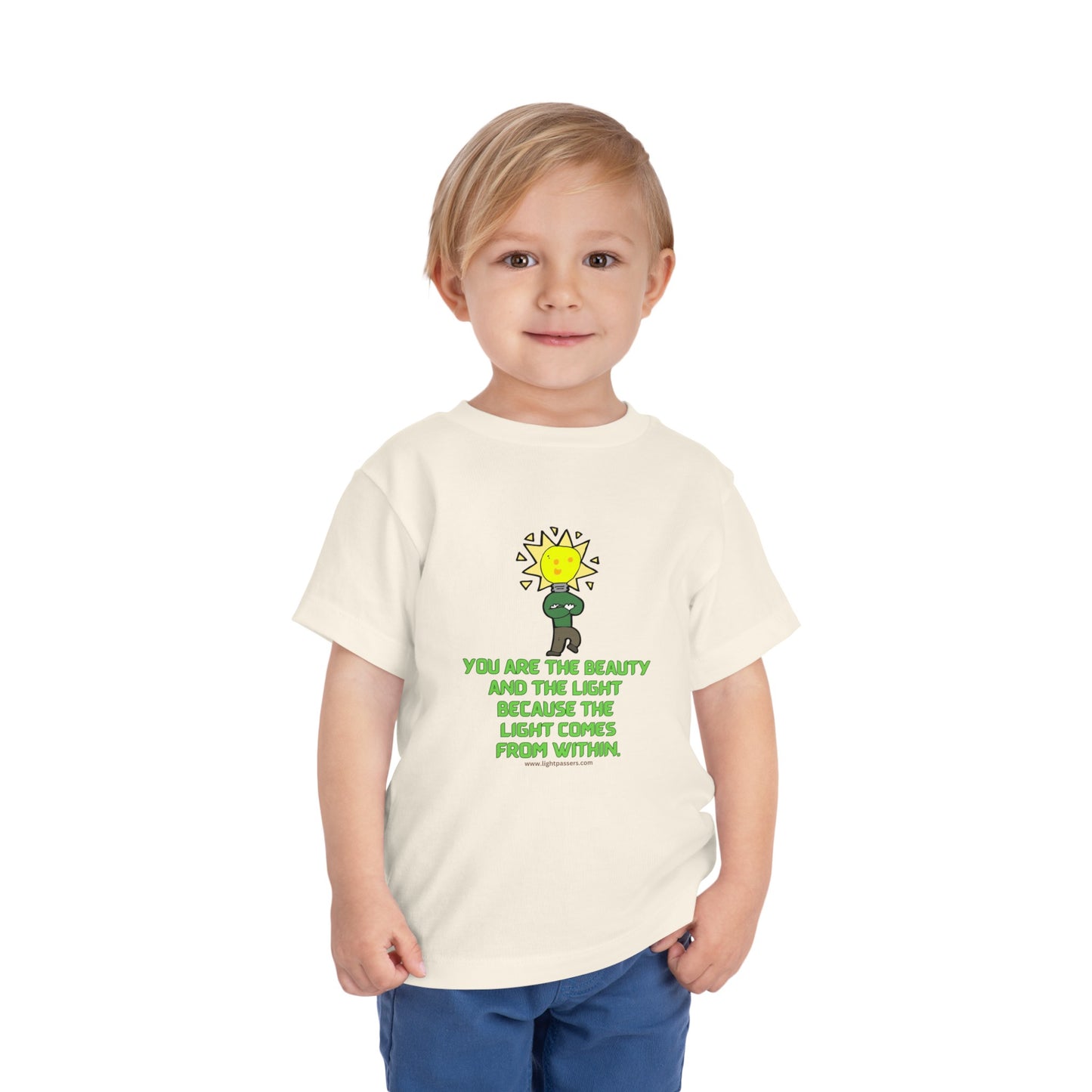 A toddler in a white Bella Canvas tee, featuring a light bulb cartoon. Made of 100% Airlume cotton, tear-away label for comfort. Ideal for stylish and comfy everyday wear.