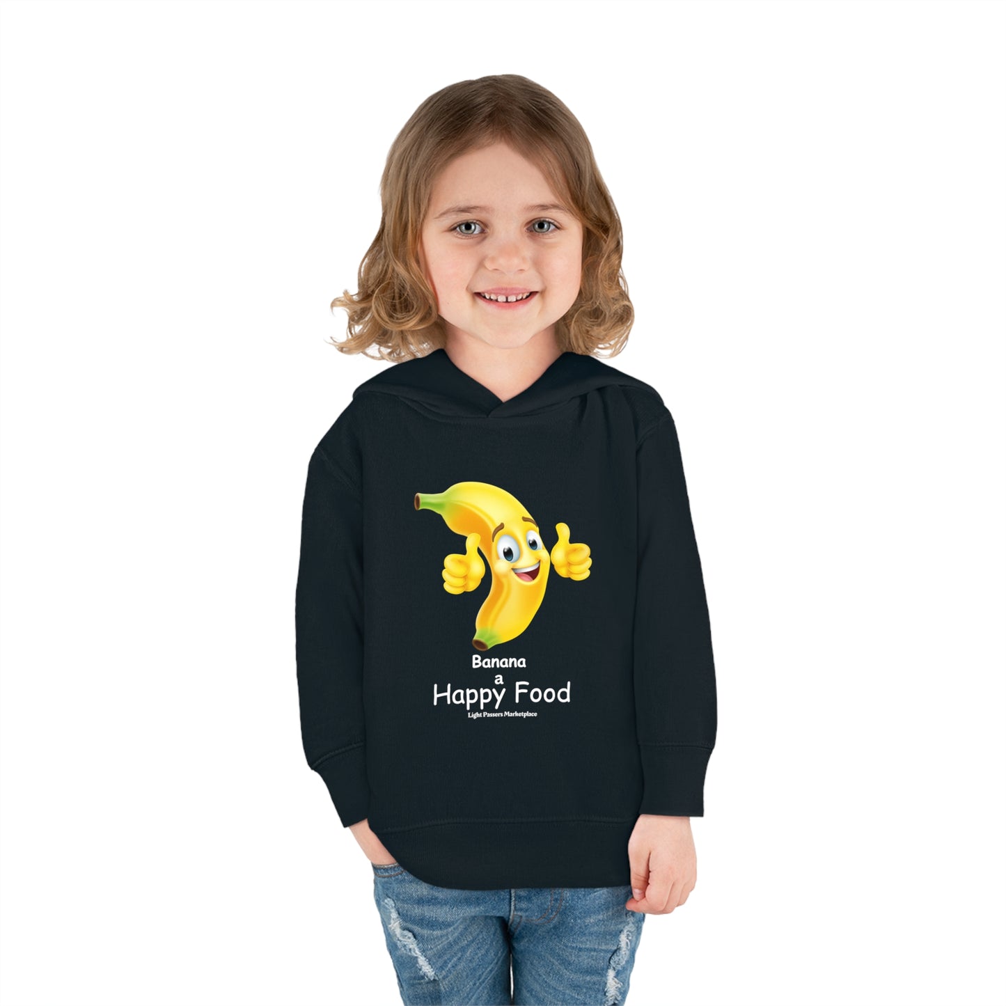 A child in a black Banana Happy Food Toddler Hooded Sweatshirt, smiling, with a cartoon banana design, showcasing jersey-lined hood, side-seam pockets, and durable stitching for long-lasting coziness.