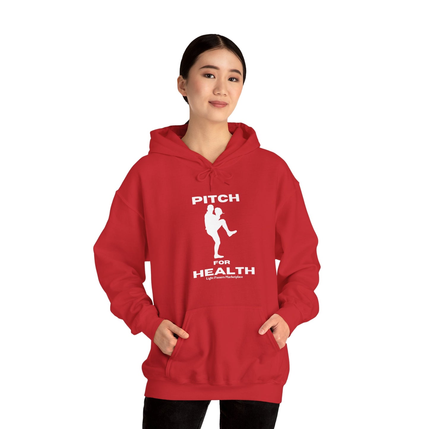 A person in a red hooded sweatshirt swinging a baseball bat, showcasing the Pitch For Health Unisex Hooded Sweatshirt's cozy blend of cotton and polyester, kangaroo pocket, and color-matched drawstring.