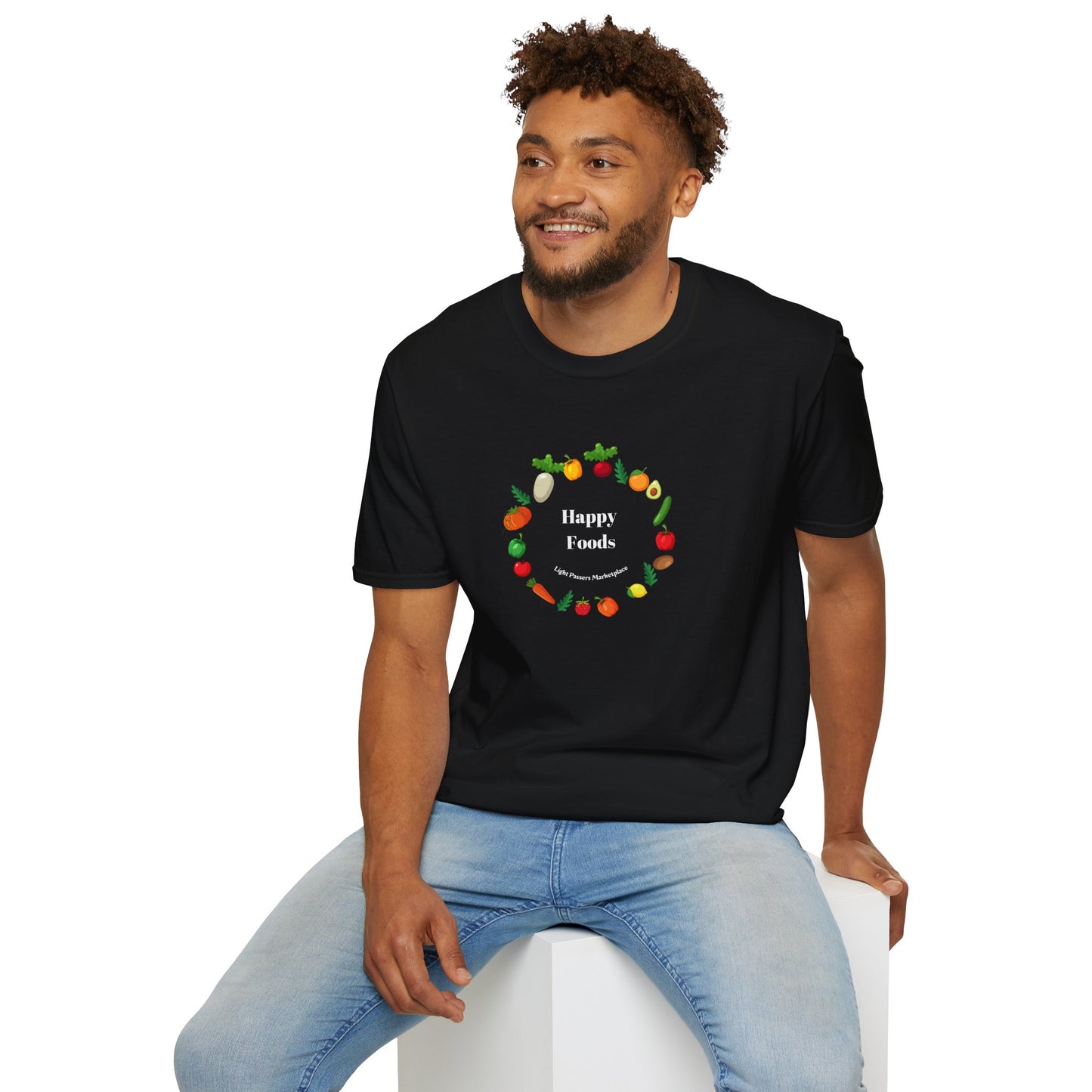 A man in a black shirt sitting on a white cube, showcasing the Happy Foods Ring Unisex T-Shirt. Made of soft 100% cotton, featuring twill tape shoulders for durability and a clean crew neckline.