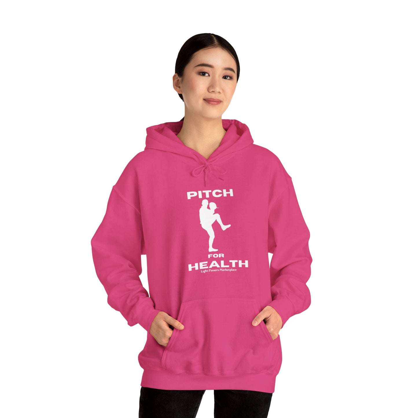 A woman in a pink hoodie, showcasing the Pitch For Health Unisex Hooded Sweatshirt. Made of cotton and polyester, this cozy sweatshirt features a kangaroo pocket and color-matched drawstring for style and comfort.