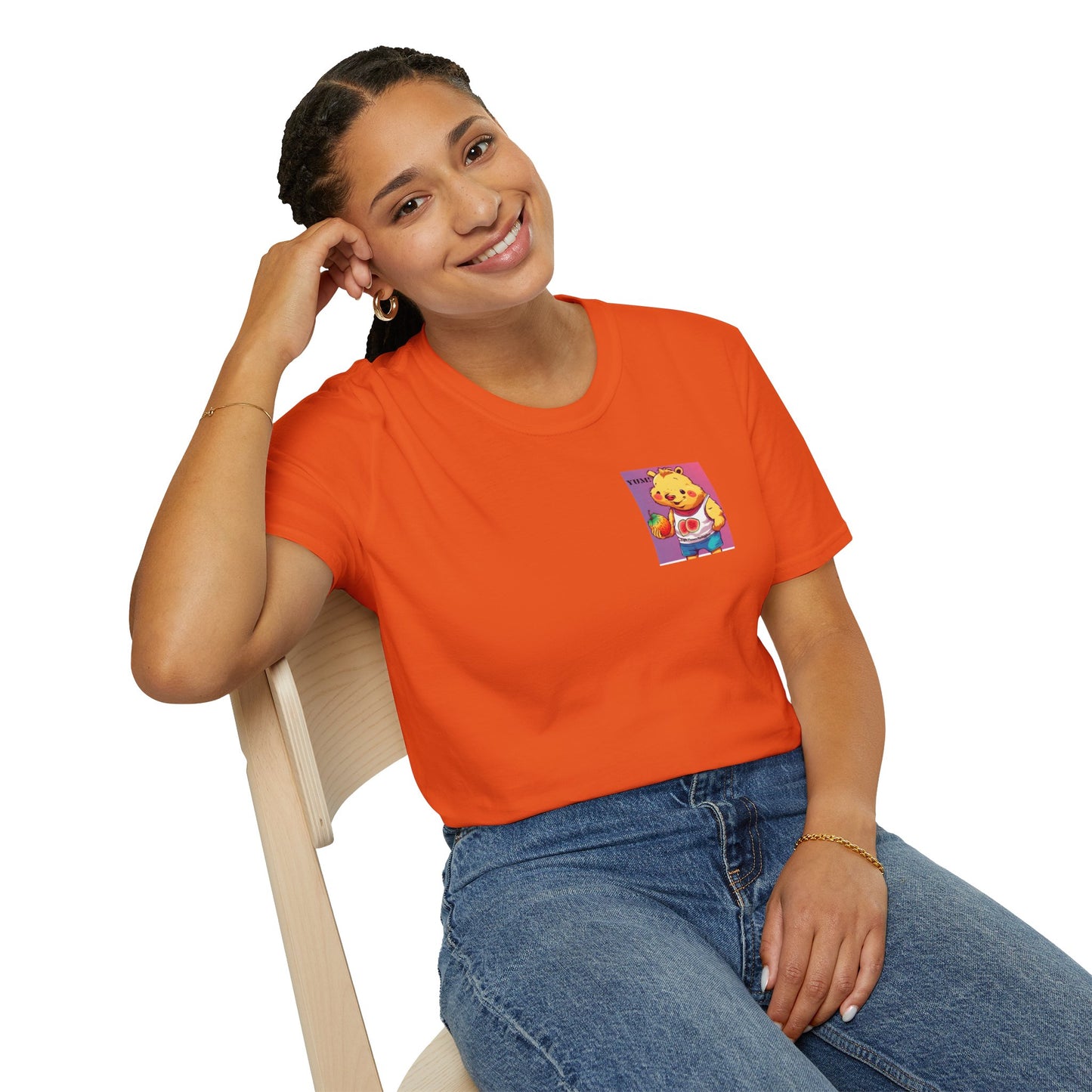 A woman in an orange shirt sits on a chair, showcasing the Yum Strawberries Unisex T-Shirt's comfort and style. Made of soft, 100% cotton with twill tape shoulders for durability, this tee offers a versatile, classic fit.