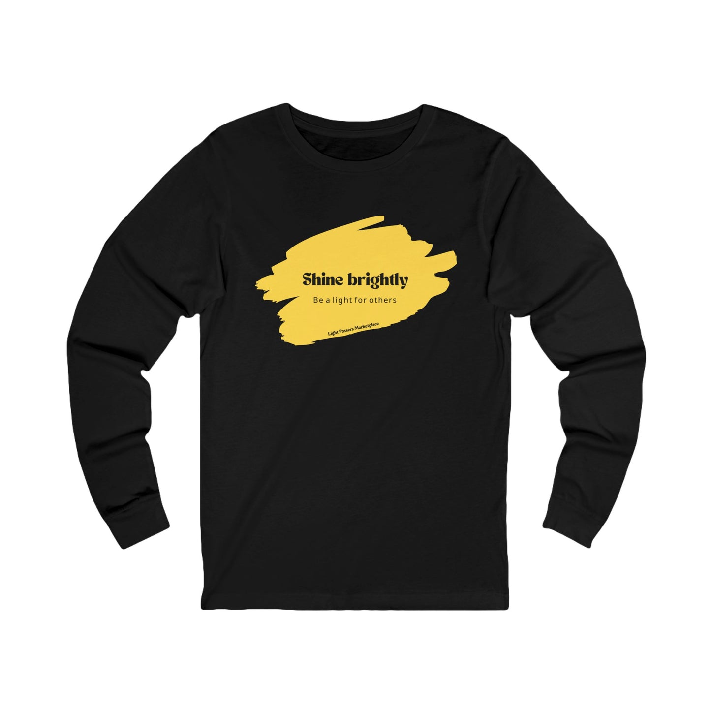 The Light Adult Unisex Long Sleeve Tee features black fabric with yellow paint accents, emphasizing its positive Shine Brightly Be the Light for Others message.