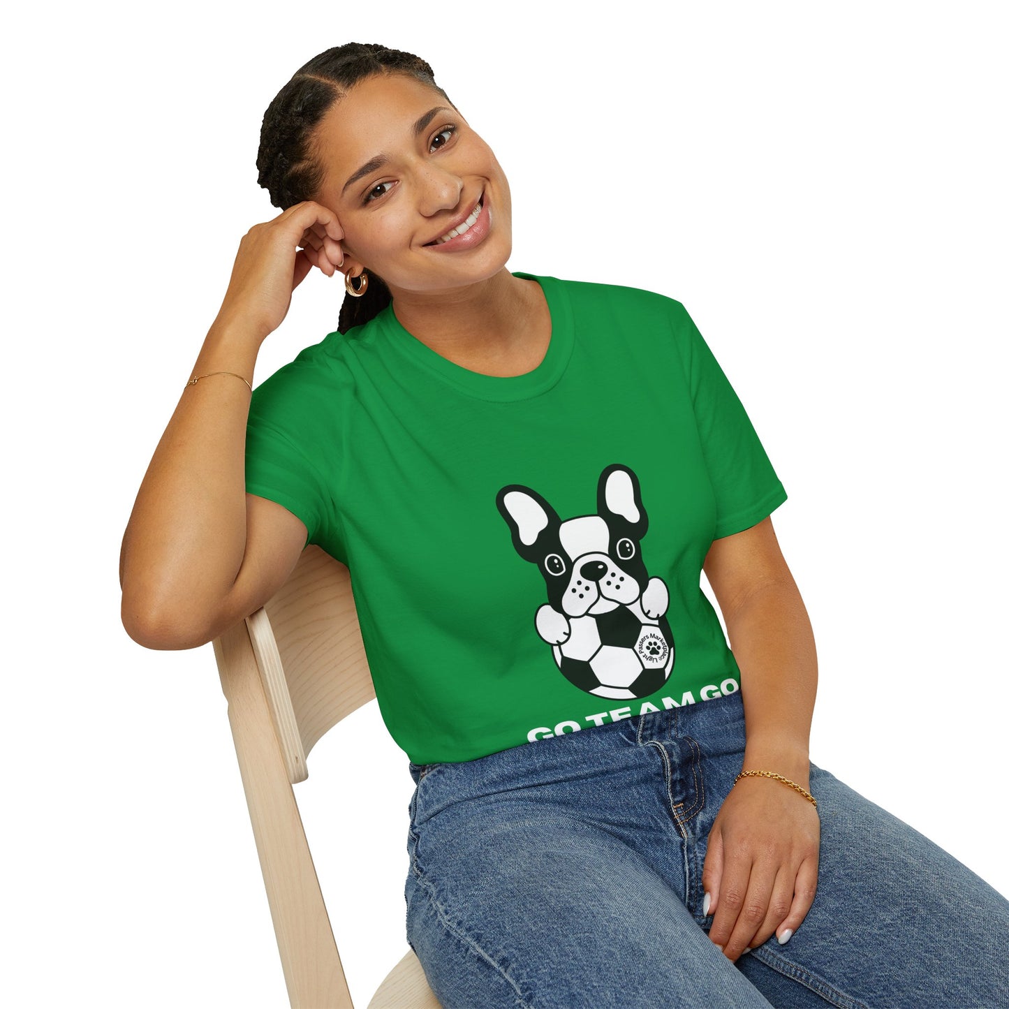 A woman in a green shirt with a dog design sits on a chair, showcasing the Soccer Dog Unisex T-Shirt. Soft 100% cotton material, twill tape shoulders, and ribbed collar for comfort and durability.