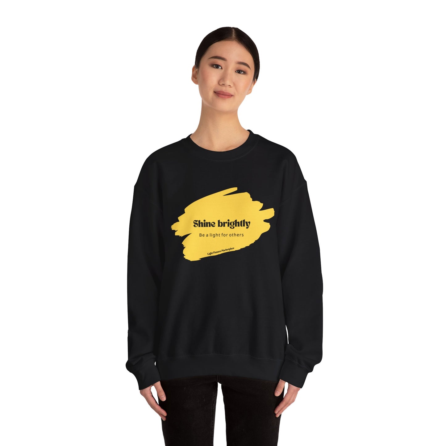 The Light Inspirational Crewneck Sweatshirt Adult Unisex features a black design with yellow paint accents, offering warmth and positivity for casual wear.
