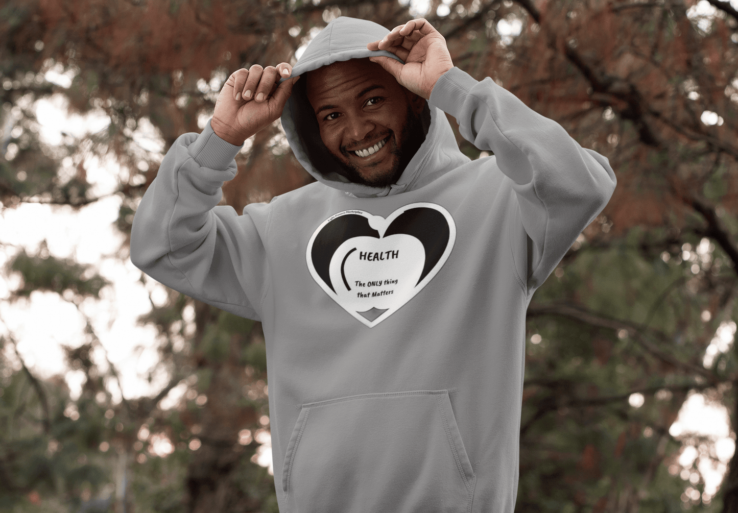 Man smiling in a Health Happy Food Apple Adult Unisex Hoodie, showcasing its relaxed fit, spacious kangaroo pocket, and stylish color-matched drawstring.