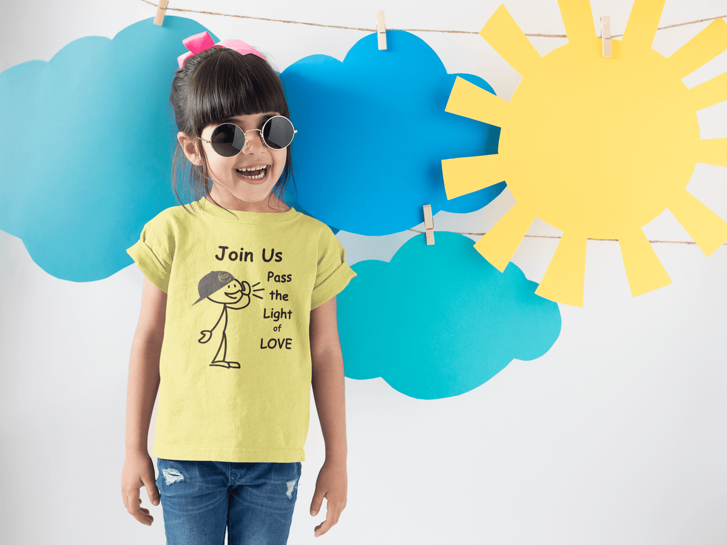 Youth wearing The Light Love and Peace Call Pass the Light of Love T-shirt, smiling with sunglasses, highlighting the tee's comfortable fit and durable fabric.