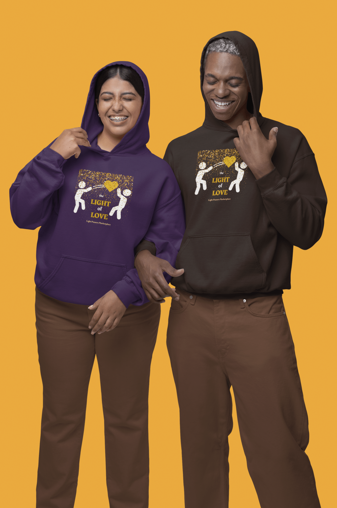 A man and woman in hoodies, one wearing a purple sweatshirt, the other in brown and white, showcasing the Light of Love Gold Heart Unisex Hooded Sweatshirt's cozy, stylish design with a kangaroo pocket and color-matched drawstring.