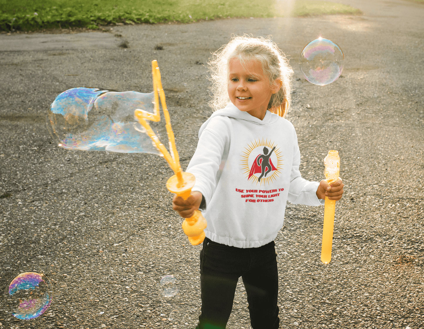 A girl holds bubbles and two poles, embodying playful outdoor fun with the Use Your Powers Toddler Hooded Sweatshirt, featuring durable design and side-seam pockets for cozy adventures.