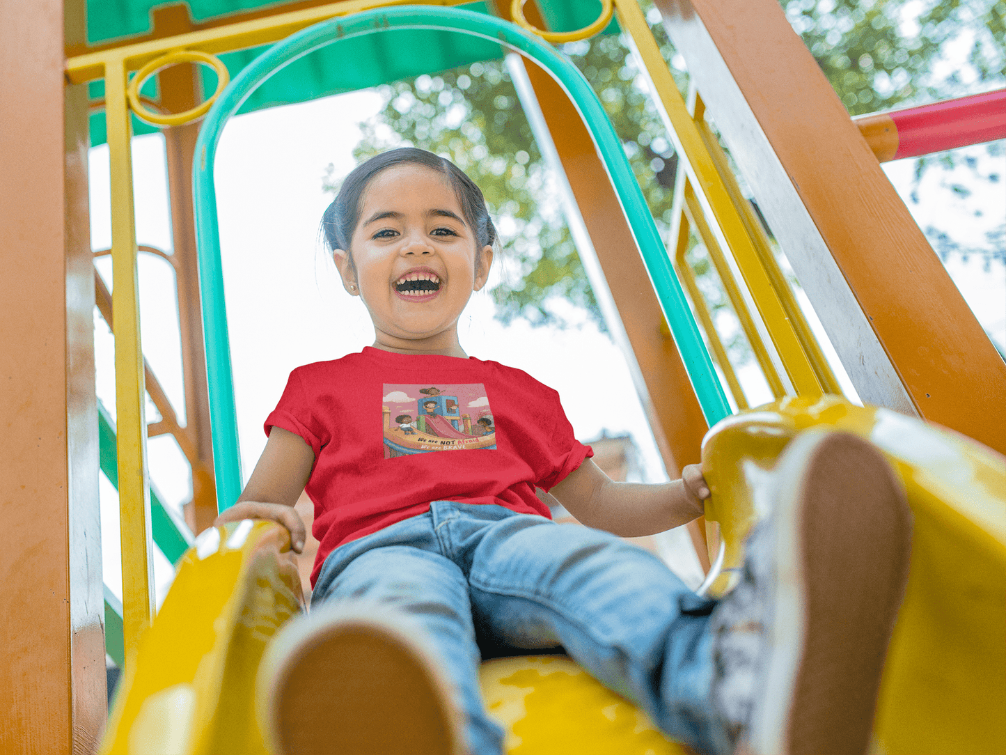 A smiling toddler in the We are Brave Toddler T-shirt, featuring a durable print on soft 100% combed cotton fabric. Perfect for sensitive skin.