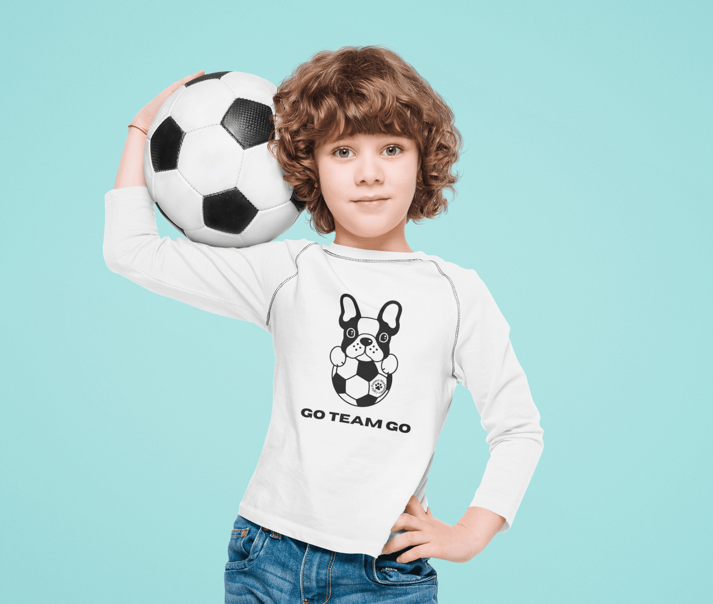 Child holding a football in a Soccer Dog Go Team Go Youth Long Sleeve, showcasing its athletic fit and moisture-wicking fabric for young soccer enthusiasts.
