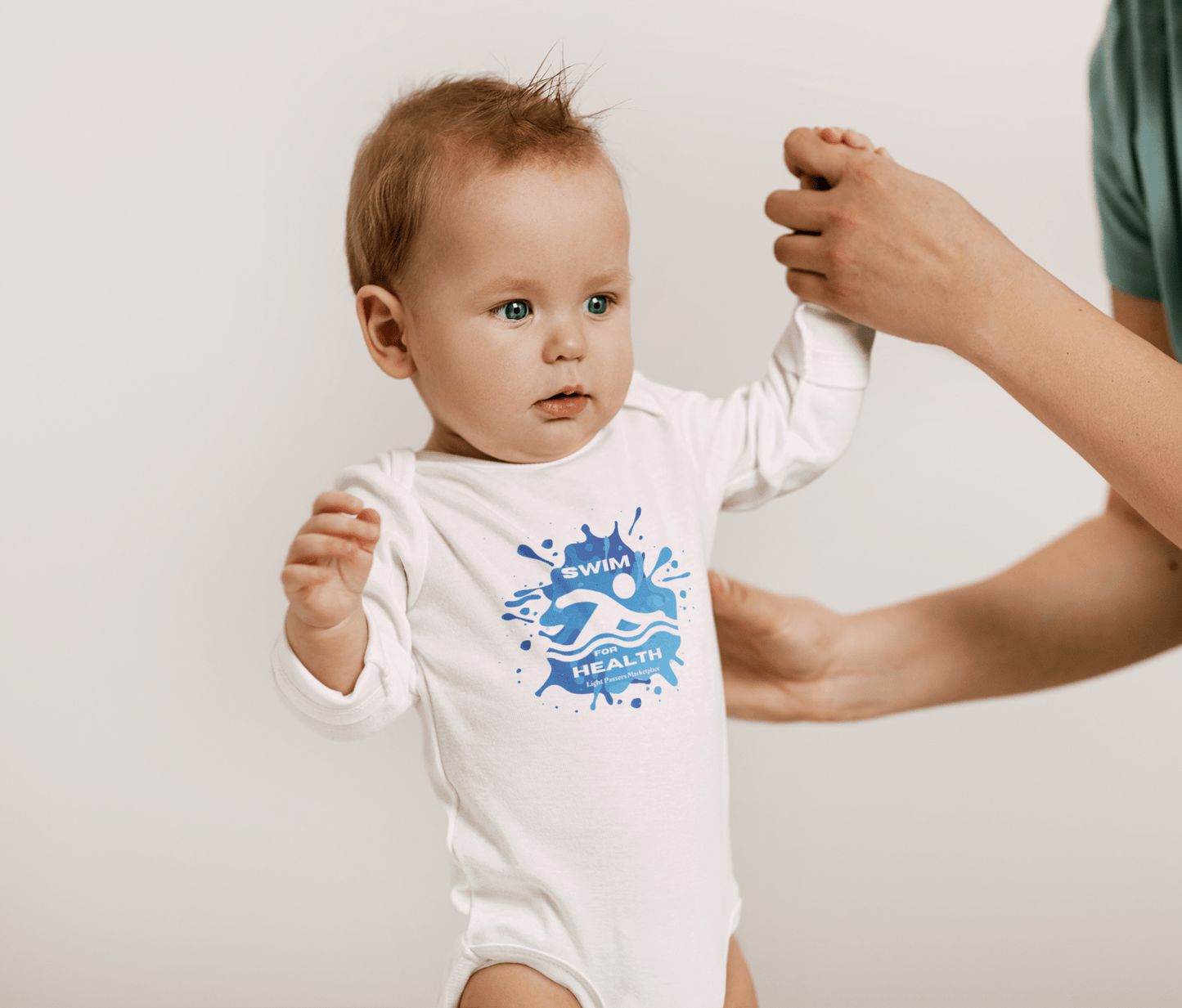 Baby in a Health Swim for Health Long Sleeve Onesie, showcasing ribbed knit binding and plastic snaps, held by a person.