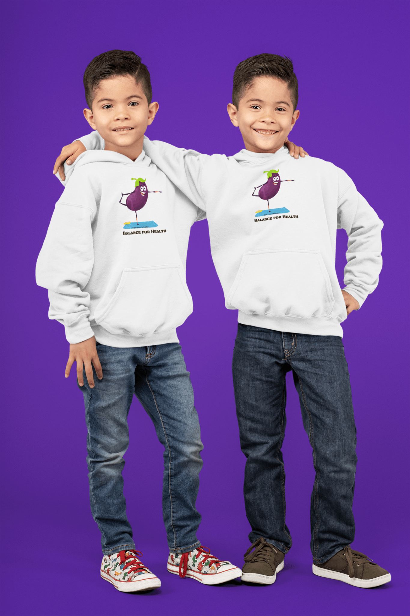 Two boys in white sweatshirts, one with a cartoon eggplant design, showcasing the Eggplant Balance Youth Hooded Sweatshirt. Kangaroo pocket, soft fleece, reinforced neck, ideal for printing.