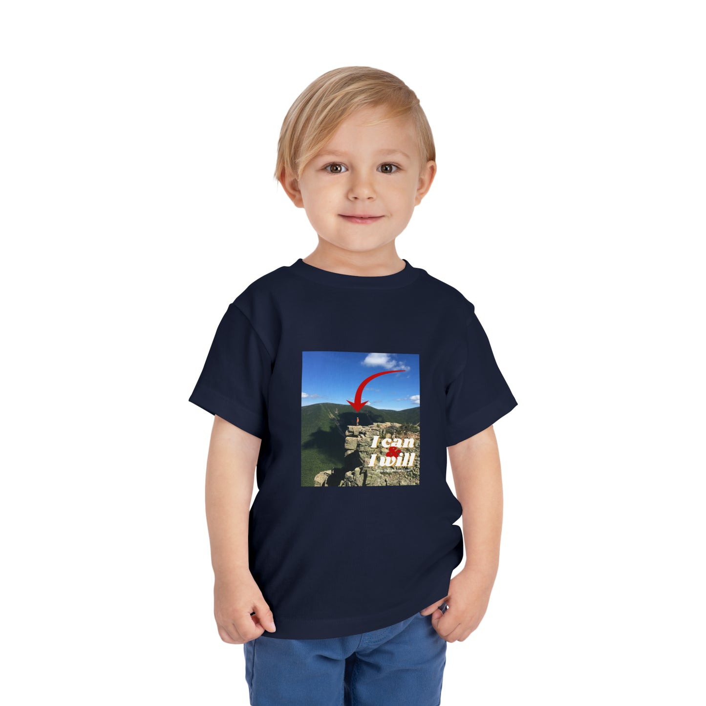 A boy in a blue shirt stands confidently on a cliff, embodying the spirit of the I Can and I Will Hiking Toddler T-shirt. Made of 100% Airlume cotton for comfort and style.