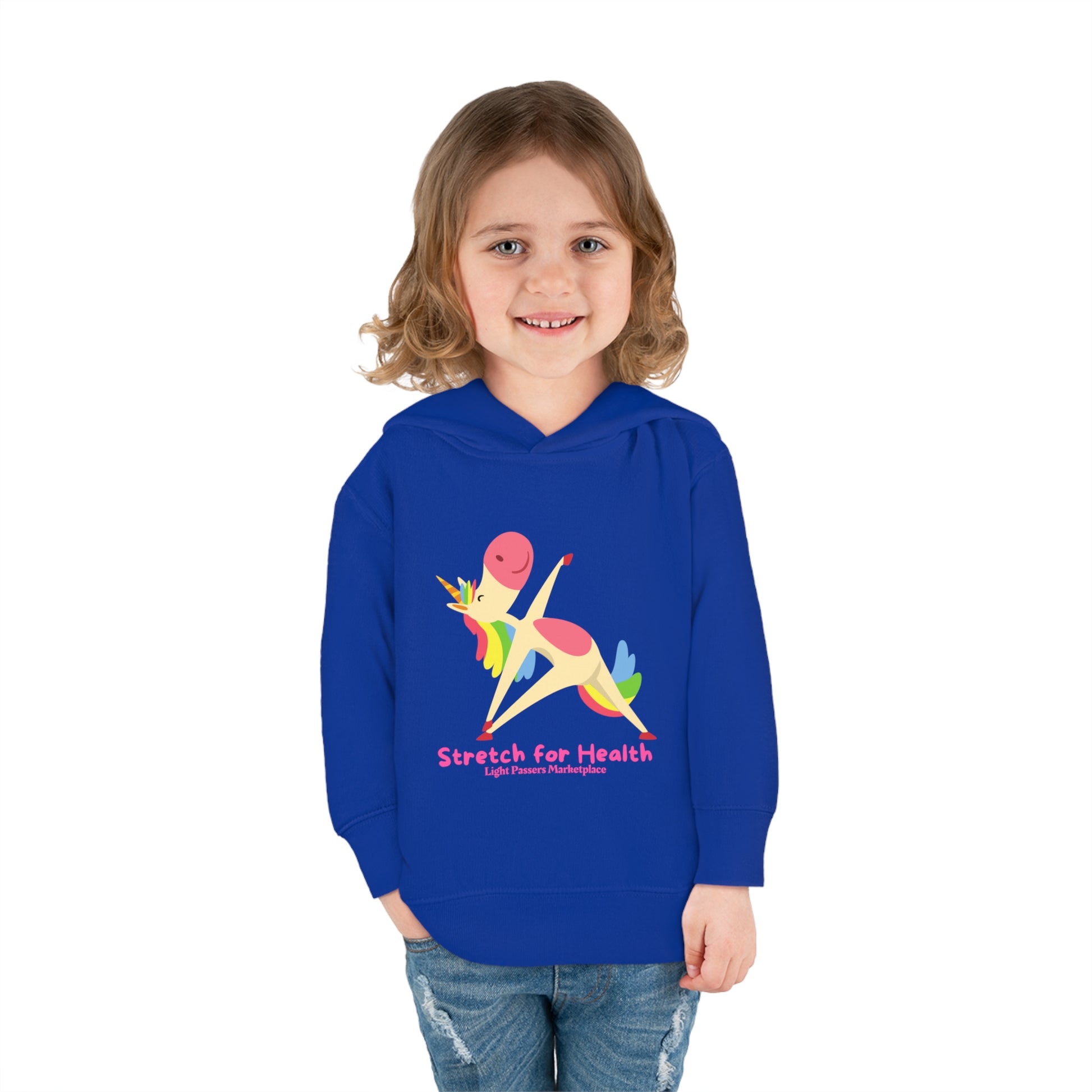 A toddler in a blue hoodie with a cartoon unicorn design, smiling at the camera. Features jersey-lined hood, side seam pockets, and durable stitching for lasting comfort.