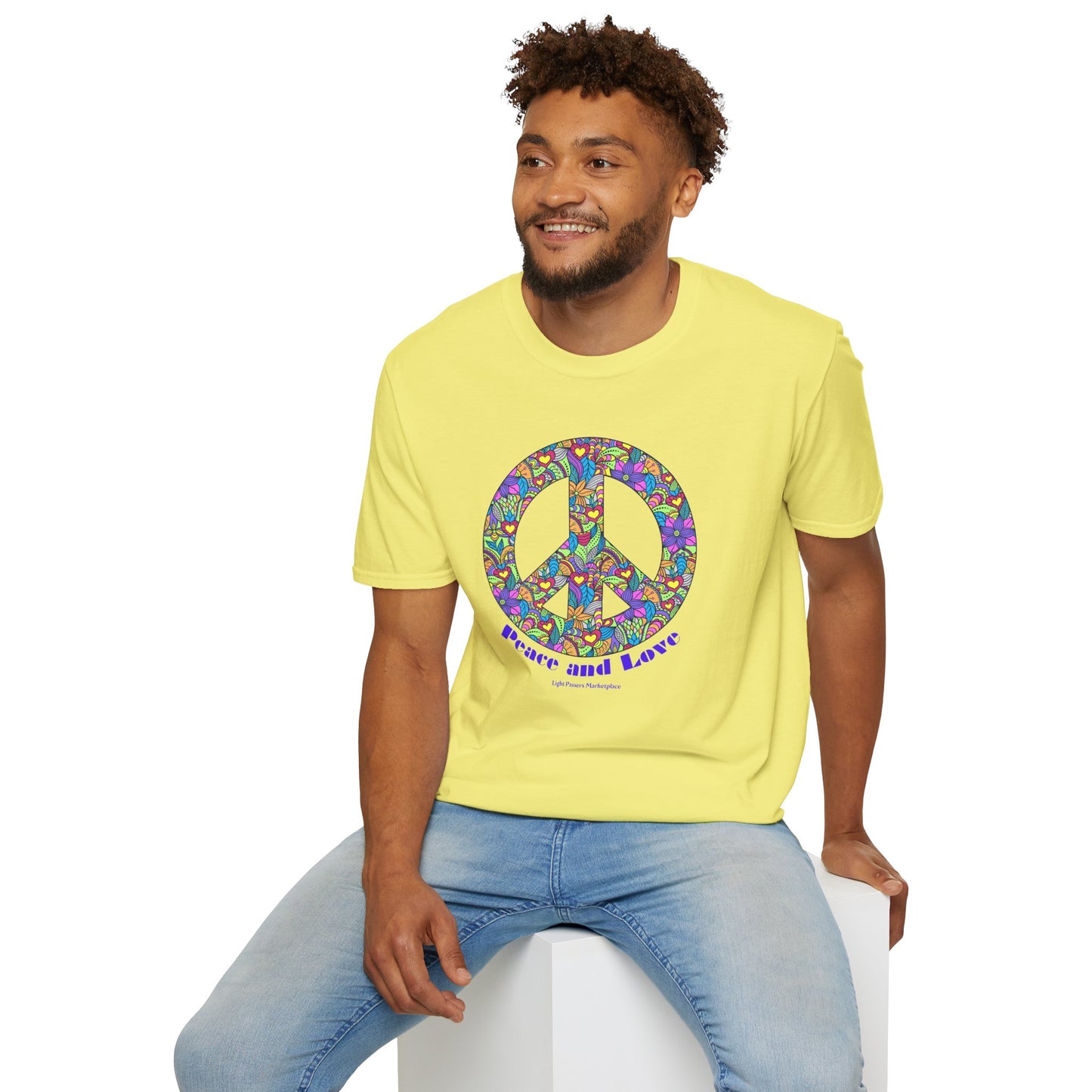 A man wearing a yellow shirt with a peace sign sits on a cube, showcasing the Peace sign with flowers Unisex T-shirt. Made of soft 100% cotton, featuring twill tape shoulders and a ribbed collar.