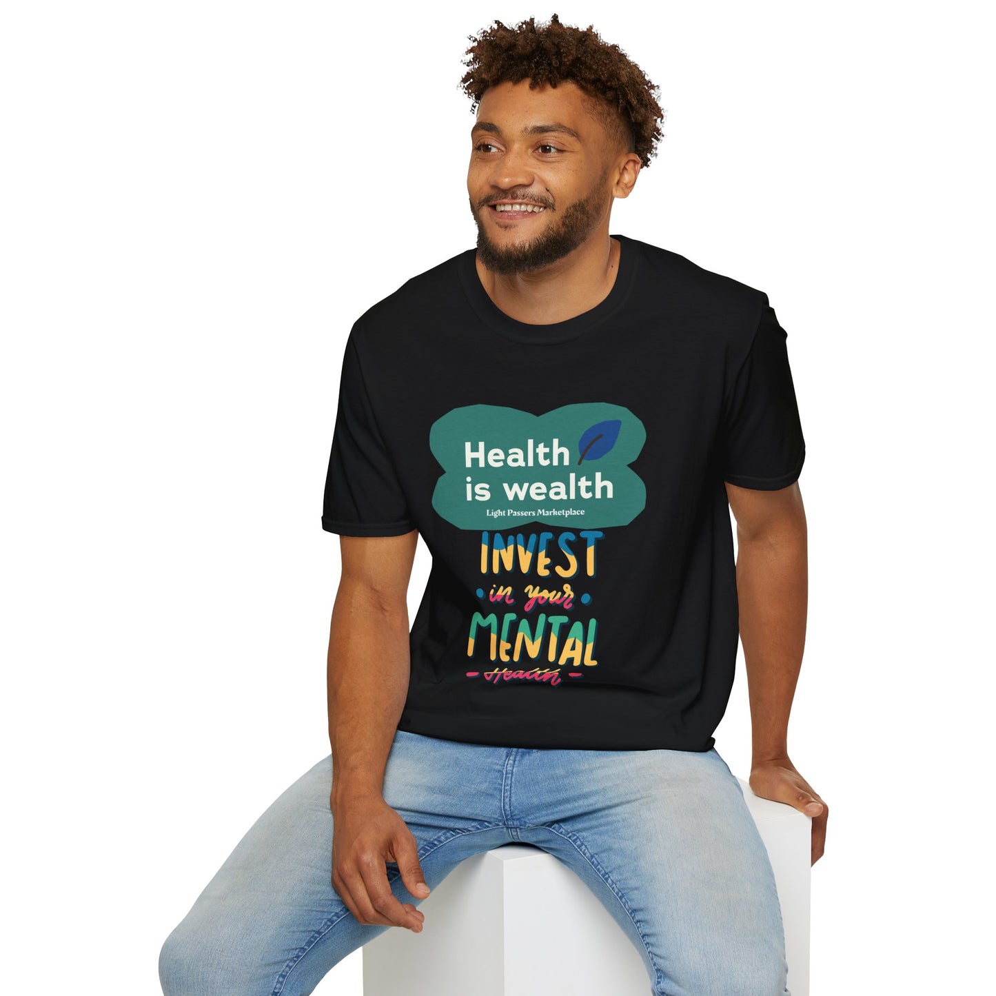 A man in a black shirt sits on a cube, showcasing the Invest in Mental Health Unisex T-shirt. Made of soft 100% cotton, with twill tape shoulders for durability and a clean crew neckline.