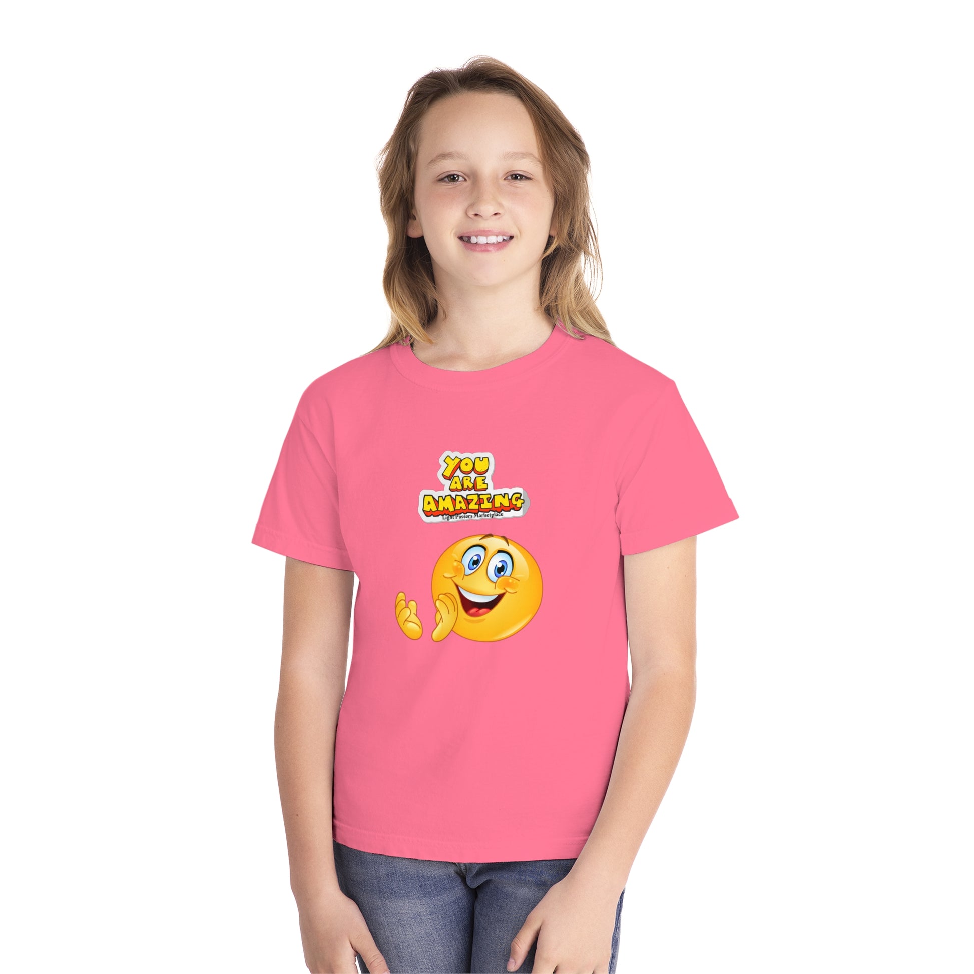 A girl in a pink shirt, close-up, showcasing the You are Amazing Clap Youth T-shirt. Made of 100% combed ringspun cotton, soft-washed, and garment-dyed for comfort and durability.